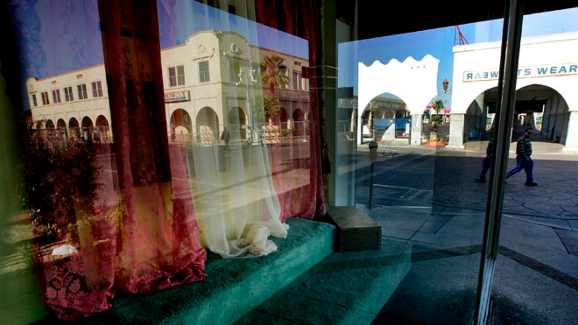 FILE - This April 15, 2010 file photo, a storefront window sits empty as downtown Calexico, Calif. is reflected in the glass. The U.S. Justice Department issued a scathing review Wednesday, May 18, 2016, of the small town's police practices in a big drug and immigrant smuggling corridor on California's border with Mexico, finding a lack of basic controls and oversight of criminal investigations, unstable leadership and other red flags. (AP Photo/Sandy Huffaker,File)