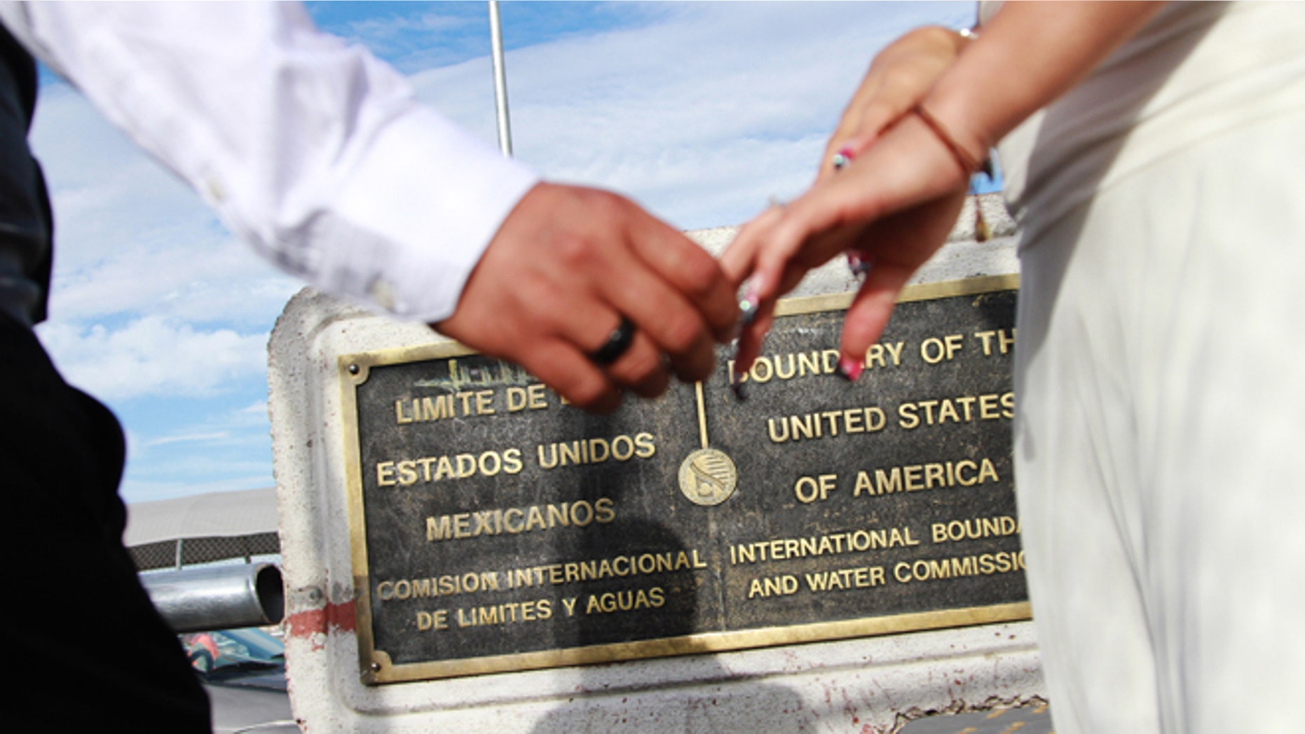 U.S. citizen Edgar Falcon, left, and Maricruz Valtierra of Mexico, hold hands at the U.S.-Mexico border where they were married, Tuesday, Aug. 27, 2013 in El Paso, Texas. Like many other couples made up of a US citizen and a foreigner, Falcon and Valtierra, who has been declared inadmissible after an immigration law violation, hope immigration reform will help them live together in the U.S. (AP Photo/Juan Carlos Llorca)