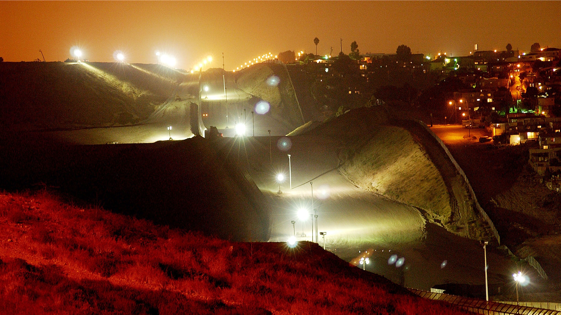 394677 03: Lights, fences, and barren land create an erie no man's land between the Tijuana, Mexico neighborhood of Colonia Libertad (R) and the U.S., September 19, 2001 east of San Ysidro, CA. Operation Gatekeeper's border crackdown of recent years has created the prison-like appearance and has made the border easier to defend against possible terrorist crossings. (Photo by David McNew/Getty Images)