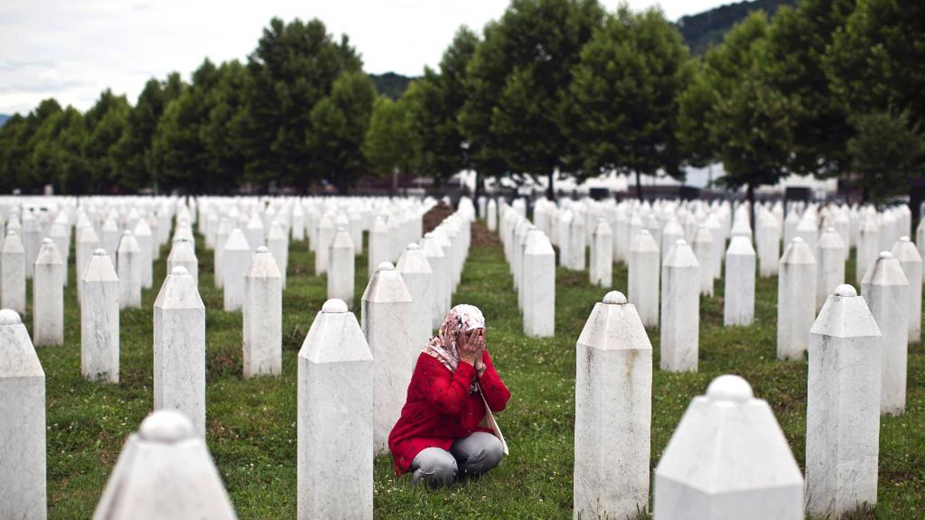 A woman prays next to a grave of her relative at the Potocari memorial complex, in Potocari, close to Srebrenica, 150 kilometers northeast of Sarajevo, Thursday, July 9, 2015. The 20th anniversary of the Srebrenica massacre, the worst crime in Europe after the Nazi era, will be marked on Saturday, July 11, 2015. (AP Photo/Marko Drobnjakovic)