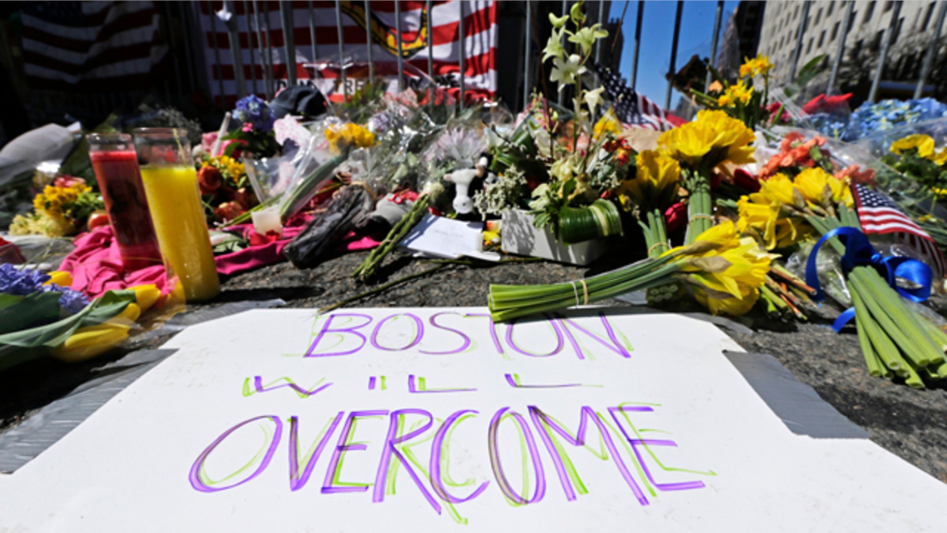 FILE - In this April 17, 2013 photograph, flowers and signs adorn a barrier at Boylston Street near the of finish line of the Boston Marathon at a makeshift memorial for victims and survivors of the bombing. Boston will mark the second anniversary of the 2013 marathon bombings Wednesday with a subdued remembrance that includes a moment of silence, the pealing of church bells and a call for kindness. (AP Photo/Charles Krupa, File)