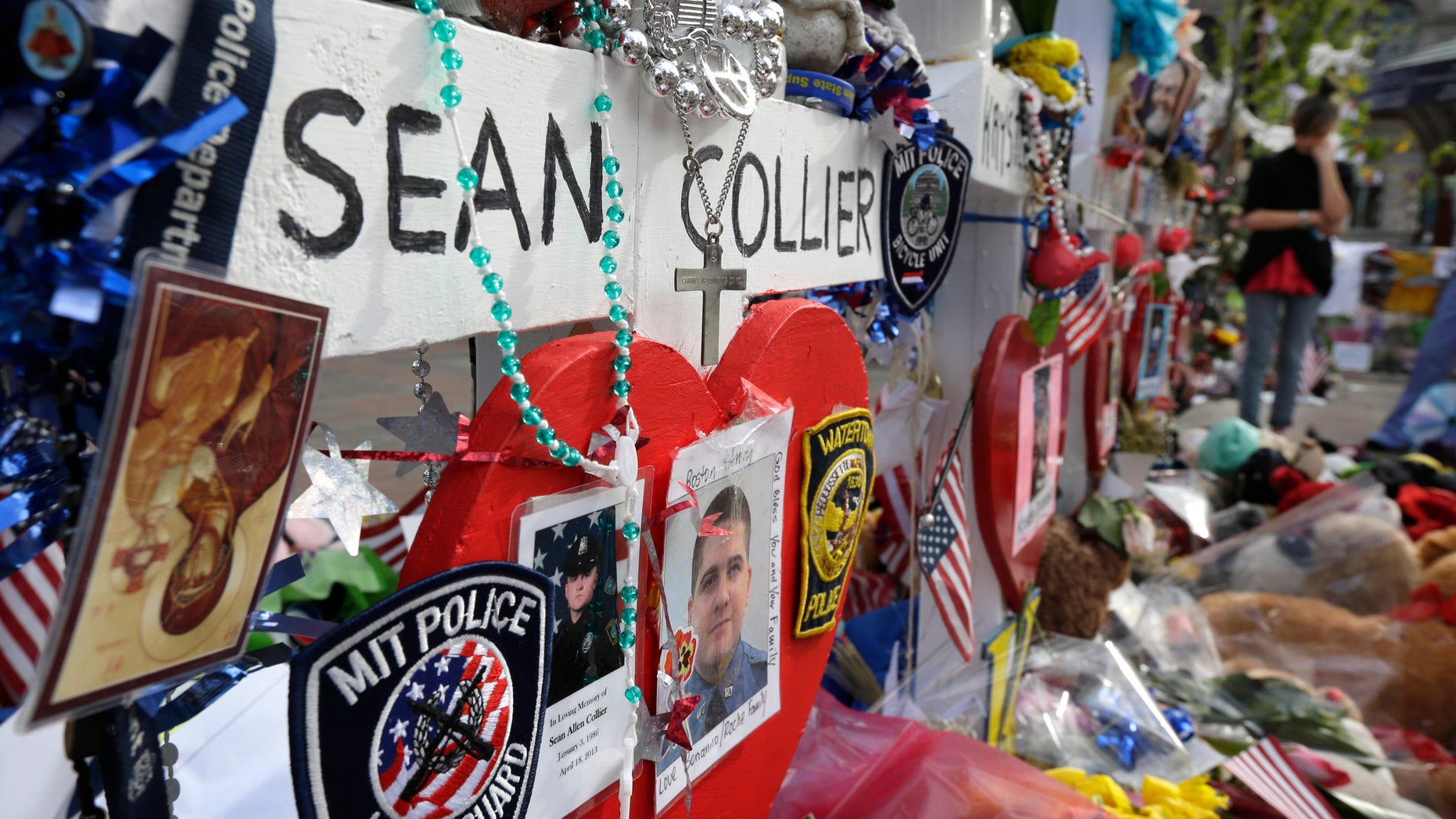 Photographs of slain Massachusetts Institute of Technology campus officer Sean Collier, center, are part of a makeshift memorial near the Boston Marathon finish line in Boston's Copley Square Tuesday, May 7, 2013 in remembrance of the Boston Marathon bombings. Authorities allege that the Boston Marathon bombing suspects were responsible for Colliers death. (AP Photo/Steven Senne)
