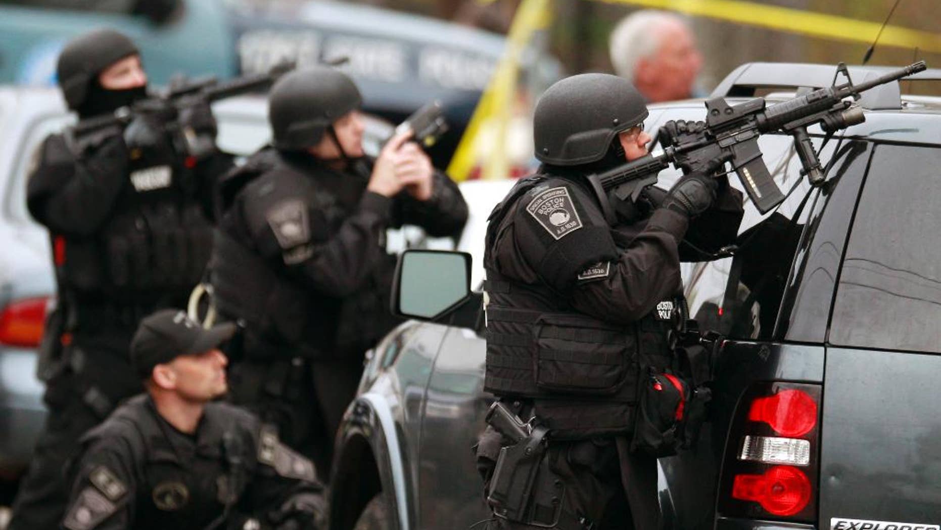 FILE - In this April 19, 2013 file photo, police in tactical gear surround an apartment building while looking for a suspect in the Boston Marathon bombings in Watertown, Mass. A Harvard University report released Thursday, April 3, 2014, on the response to the bombings was largely positive, but criticized law enforcement for the chaotic gunfight in which one suspect was killed and a police officer seriously injured, because it lacked coordination. (AP Photo/Charles Krupa, File)