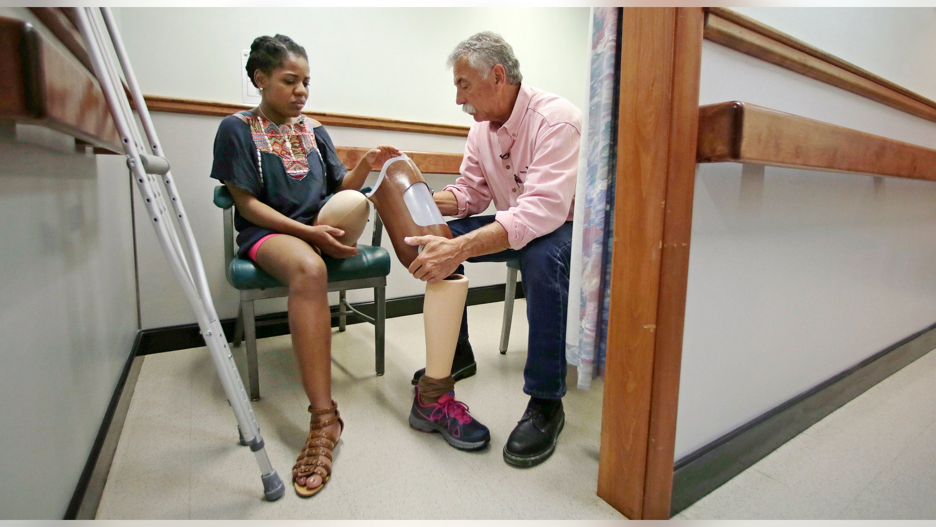 Paul Martino, president of United Prosthetics, talks with Boston Marathon bombing survivor Mery Daniel, left, while helping her try on her newly-built leg at the family-owned company in the Dorchester neighborhood of Boston.