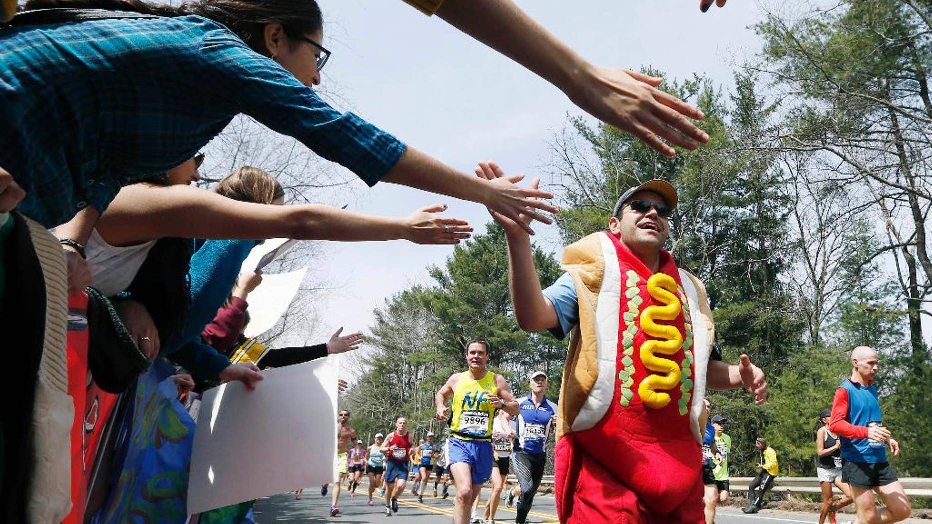 FILE -- In this April 15, 2013 file photo, a man dressed as a hot dog runs through Wellesley, Mass., during the 117th running of the Boston Marathon. Security will be tightened for the 2014 Boston Marathon after twin explosions killed three people and injured more than 260 near the finish line of the race in 2013. New rules include a limit on the size of water bottles, restrictions on bulky costumes, and nothing covering the face.(AP Photo/Michael Dwyer, File)