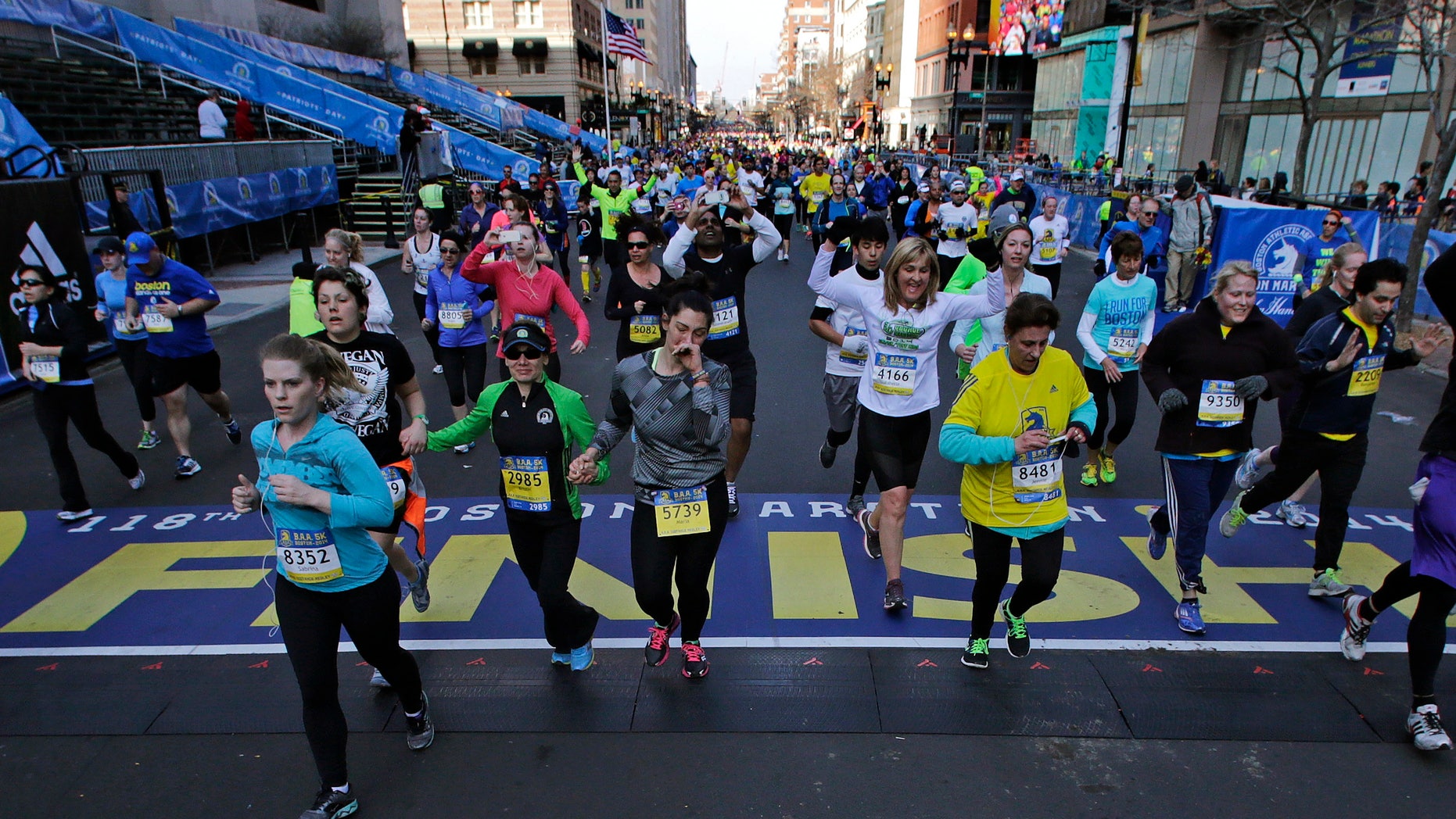 At the midpoint of the 5K race, runners cross the finish line of the Boston Marathon, Saturday, April 19, 2014, in Boston.