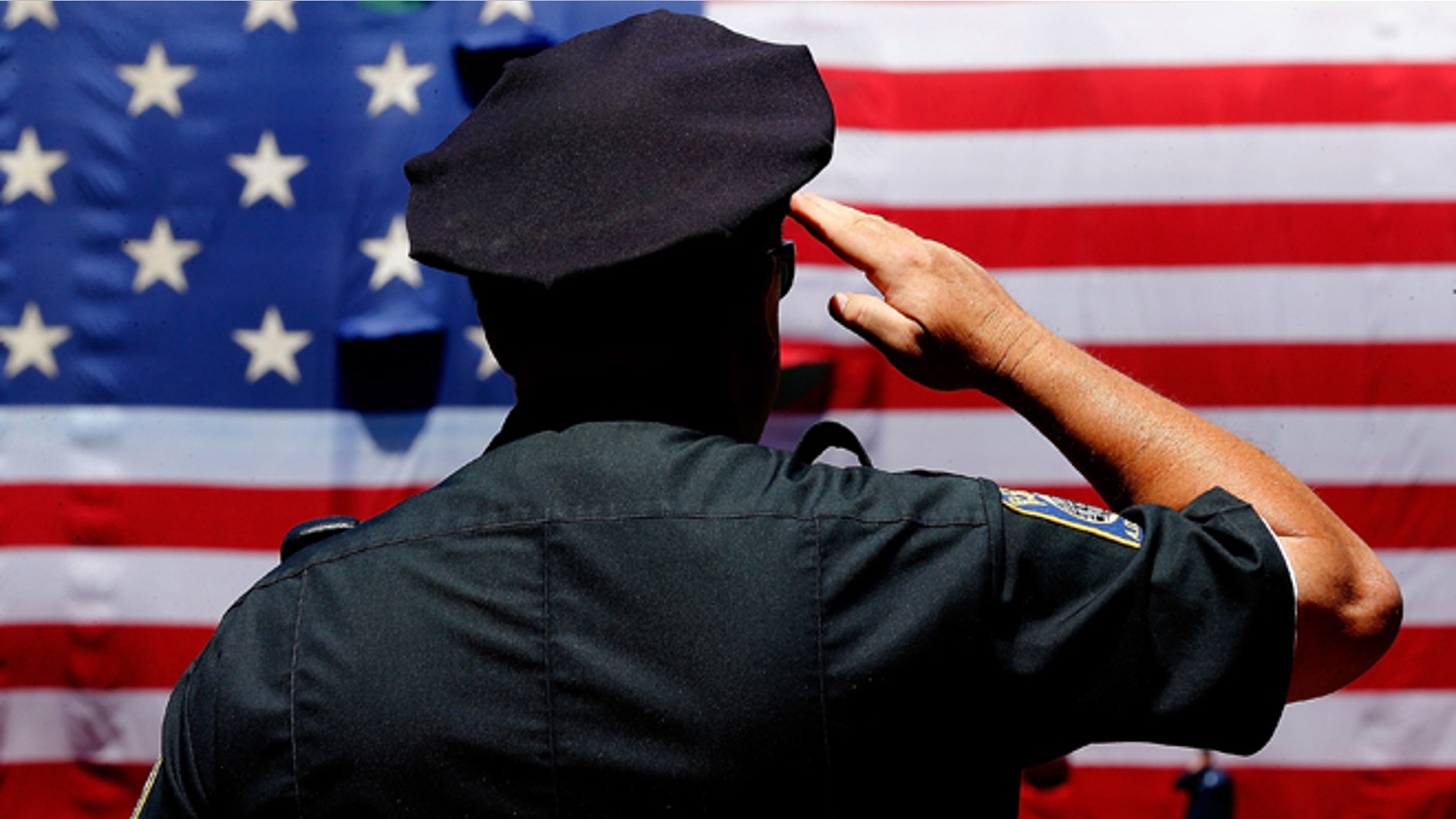 BOSTON, MA - JULY 5: A police officer salutes during the National Anthem before the first game of a doubleheader between the Baltimore Orioles and the Boston Red Sox at Fenway Park on July 5, 2014 in Boston, Massachusetts. (Photo by Jim Rogash/Getty Images)