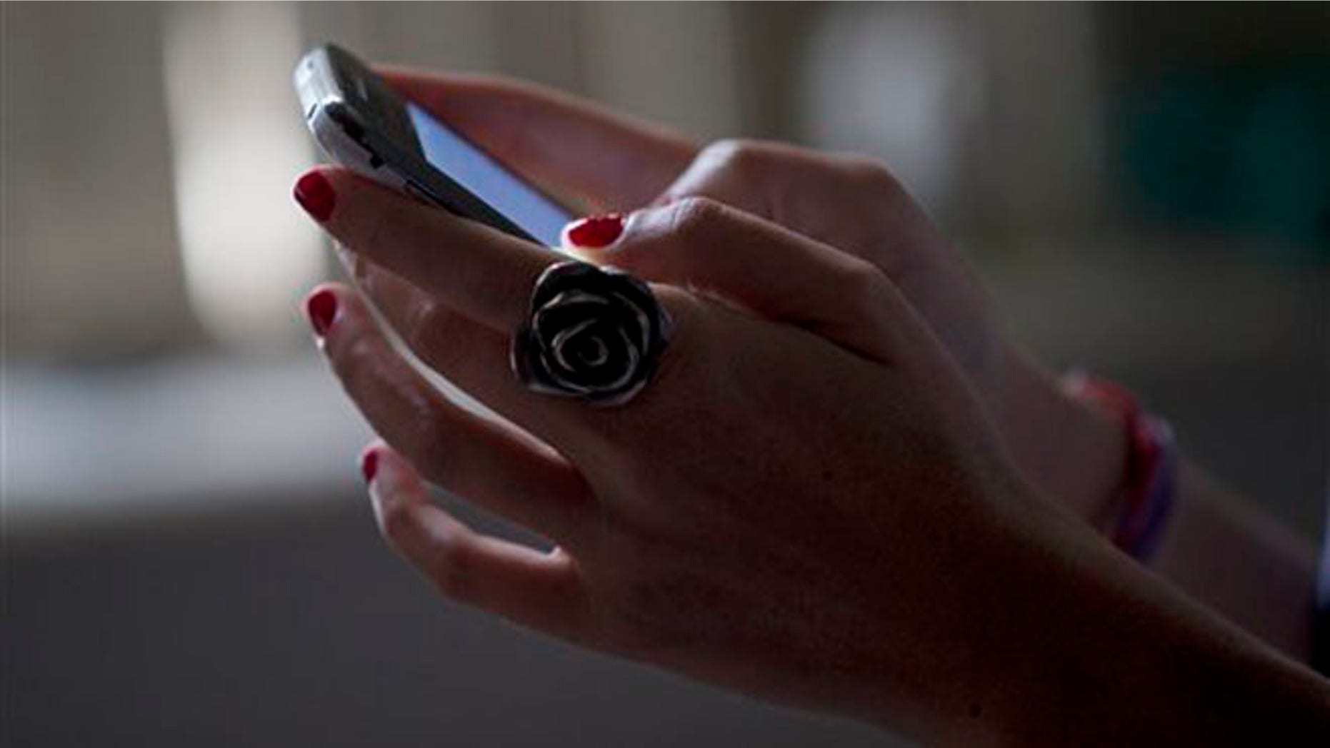 A woman poses for a photo using her smart phone in Rio de Janeiro, Brazil, Wednesday, Aug. 21, 2013. News reports say Google has removed a Brazilian Android application called "Rastreador de Namorados," or "Boyfriend Tracker" in Portuguese, from its Google Play app store, citing privacy concerns. The app, created by a 24-year-old software developer from Sao Paulo, allows users to track the location and text traffic of their unsuspecting partners. (AP Photo/Silvia Izquierdo)