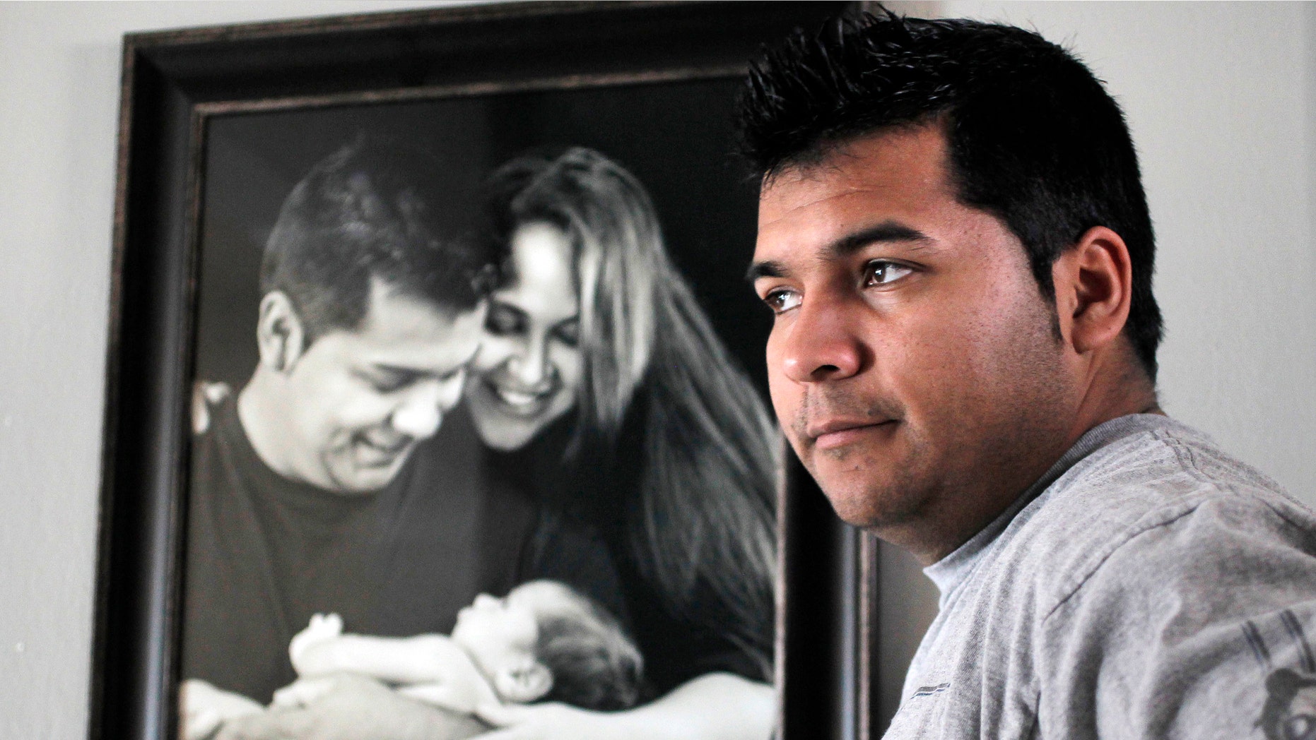 FILE - In this Friday, Jan. 3, 2014 file photo, Erick Munoz stands with an undated copy of a photograph of himself, left, with wife Marlise and their son Mateo, in Haltom City, Texas. Munozâs attorneys said in a statement Wednesday, Jan. 22, 2014, that the fetus that Marlise Munoz is carrying has several âabnormalities,â including a deformation of the lower body parts that make it impossible to determine its gender. (AP Photo/The Fort Worth Star-Telegram, Ron T. Ennis, File)