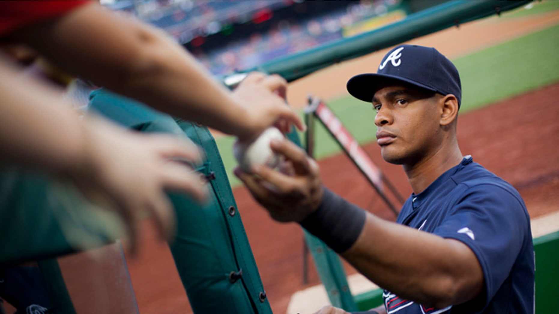 In this photo taken Sept. 3, 2015, Atlanta Braves Hector Olivera returns a ball as he signs autographs prior to start of a baseball game against the Washington Nationals, at Nationals Park in Washington. Police have arrested Olivera after a woman accused him of assault at a hotel outside in Arlington, Va. (AP Photo/Pablo Martinez Monsivais)
