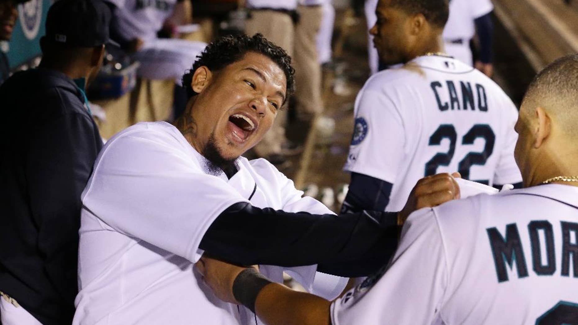 Seattle Mariners starting pitcher Felix Hernandez, left, lets out a yell and playfully grabs teammate Kendrys Morales' jersey after coming out of the baseball game after throwing eight innings against the Atlanta Braves on Tuesday, Aug. 5, 2014, in Seattle. (AP Photo/Elaine Thompson)