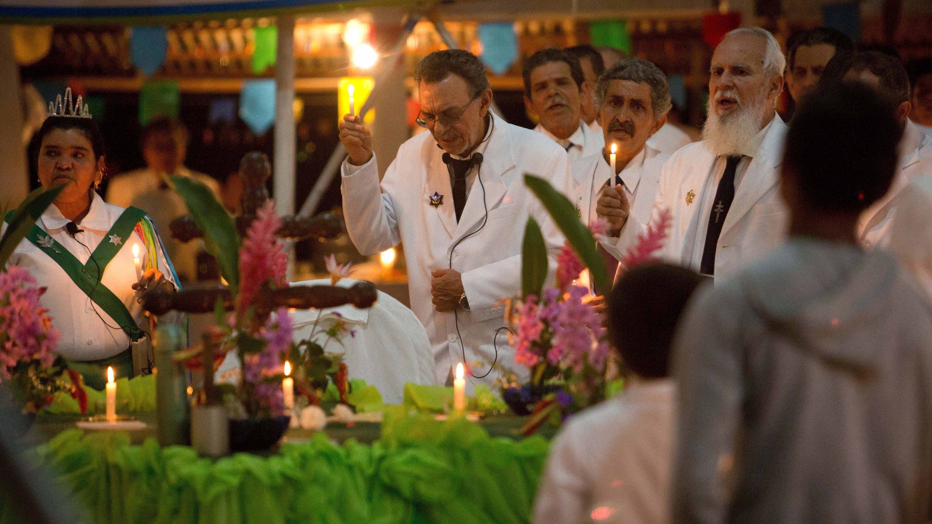 In this June 22, 2016 photo, Godfather Alfredo Gregorio, center, leads a religious service in the church of doctrine of the Holy Daime, in Ceu do Mapia, Amazonas state, Brazil. Alfredo Gregorio de Melo is son of the village founder, rubber tapper Sebastiao Mota de Melo, nicknamed Godfather Sebastiao. (AP Photo/Eraldo Peres)