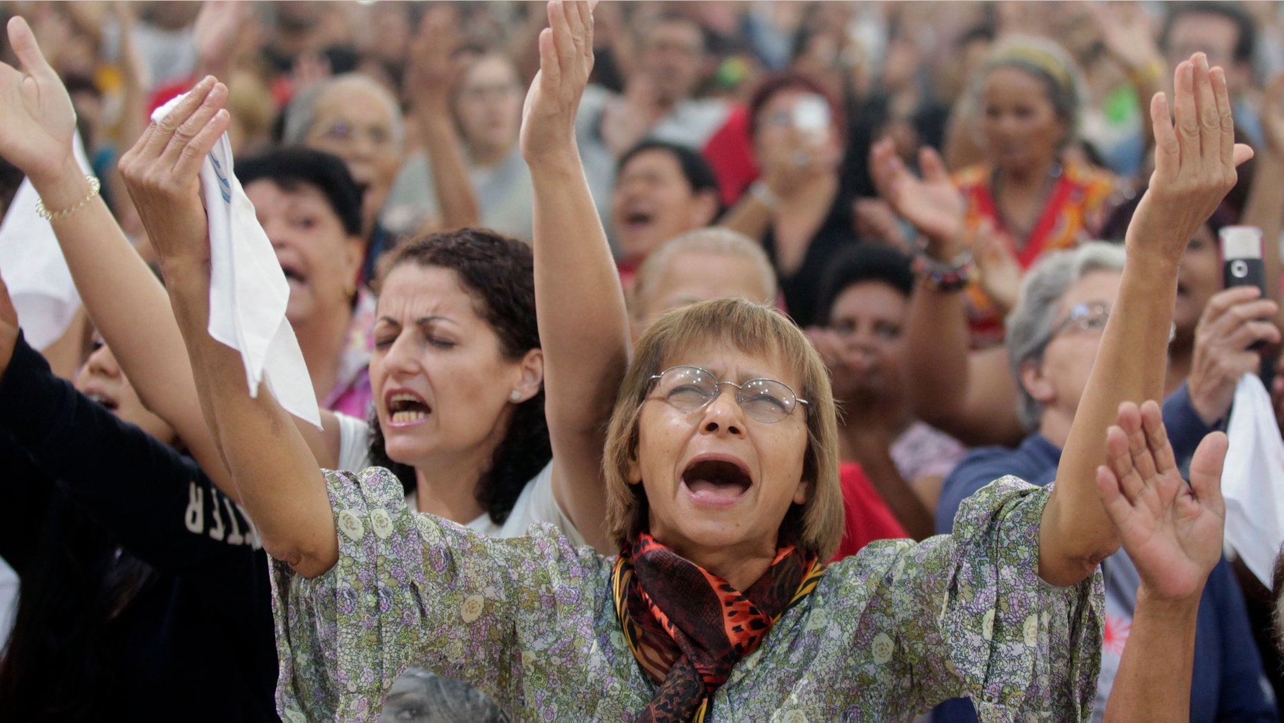 People attend a Mass led by Catholic priest Marcelo Rossi at the Mother of God sanctuary in Sao Paulo, Brazil, Saturday, Nov. 3, 2012. Rossi, a Latin Grammy-nominated Christian music singer and author of best-selling books in Brazil, inaugurated on Friday the massive new Roman Catholic church that will hold about 20,000 worshippers when complete. (AP Photo/Andre Penner)