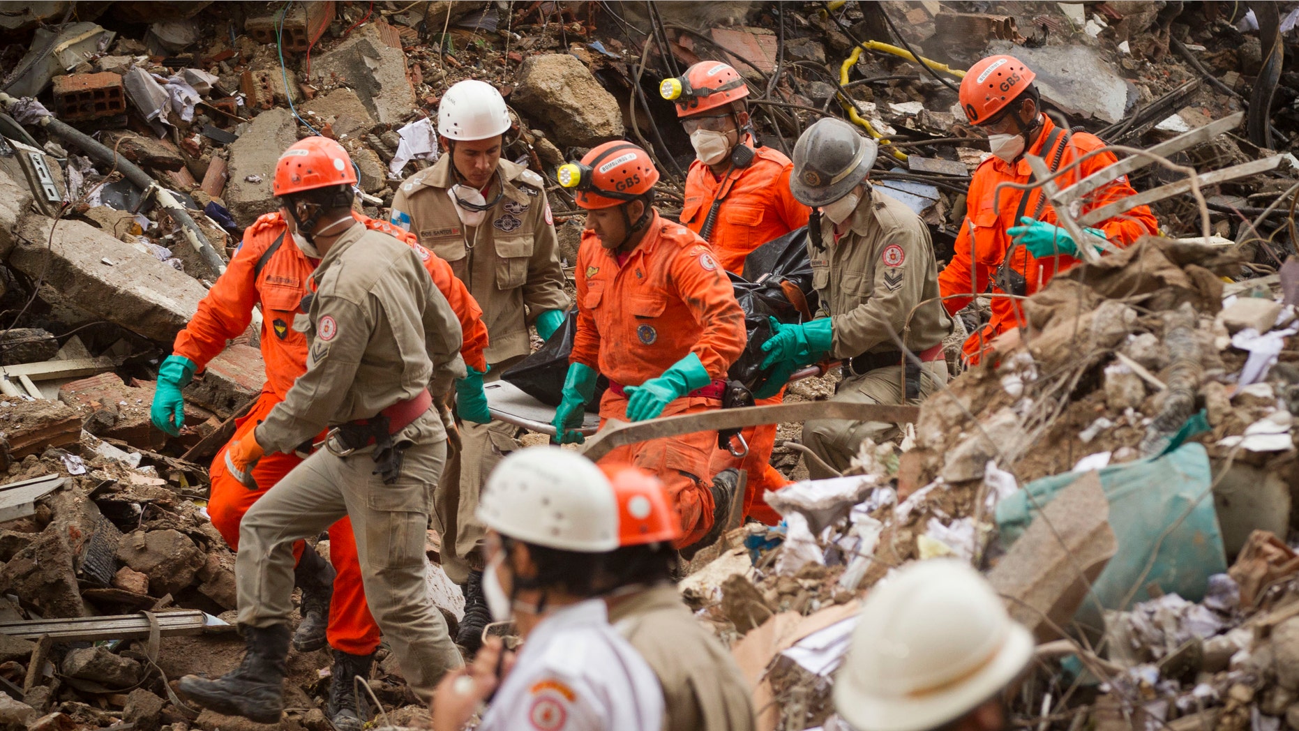 Firefighters carry away a body from the rubble after a building collapsed in downtown Rio de Janeiro, Brazil, Friday Jan. 27, 2012. The building collapsed on Wednesday, killing at least 9 people and at least 16 are still missing. (AP Photo/Victor R. Caivano)