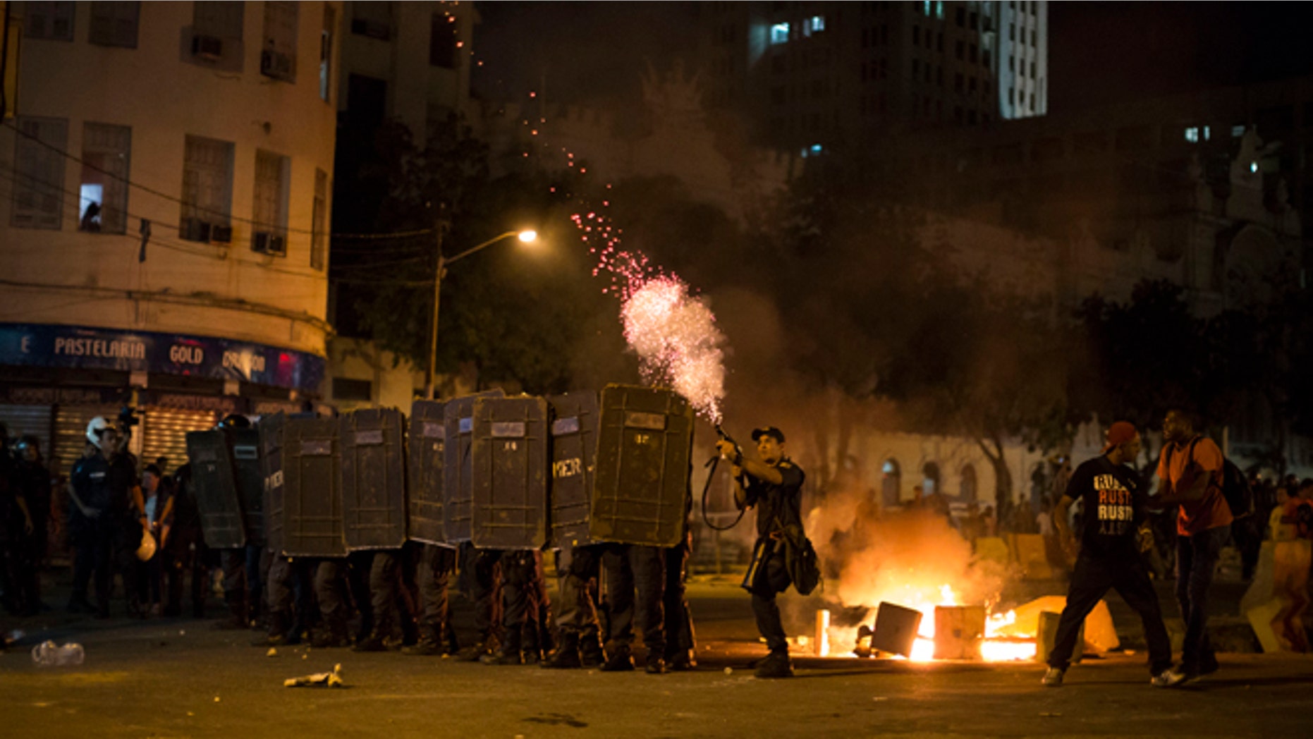 A police officer fires tear gas toward protesters during a march against bus fare hikes in Rio de Janeiro, Brazil, Friday, Jan. 8, 2016. The march, which is also taking place in other Brazilian capitals, began peacefully in downtown Rio de Janeiro but turned violent. (AP Photo/Felipe Dana)