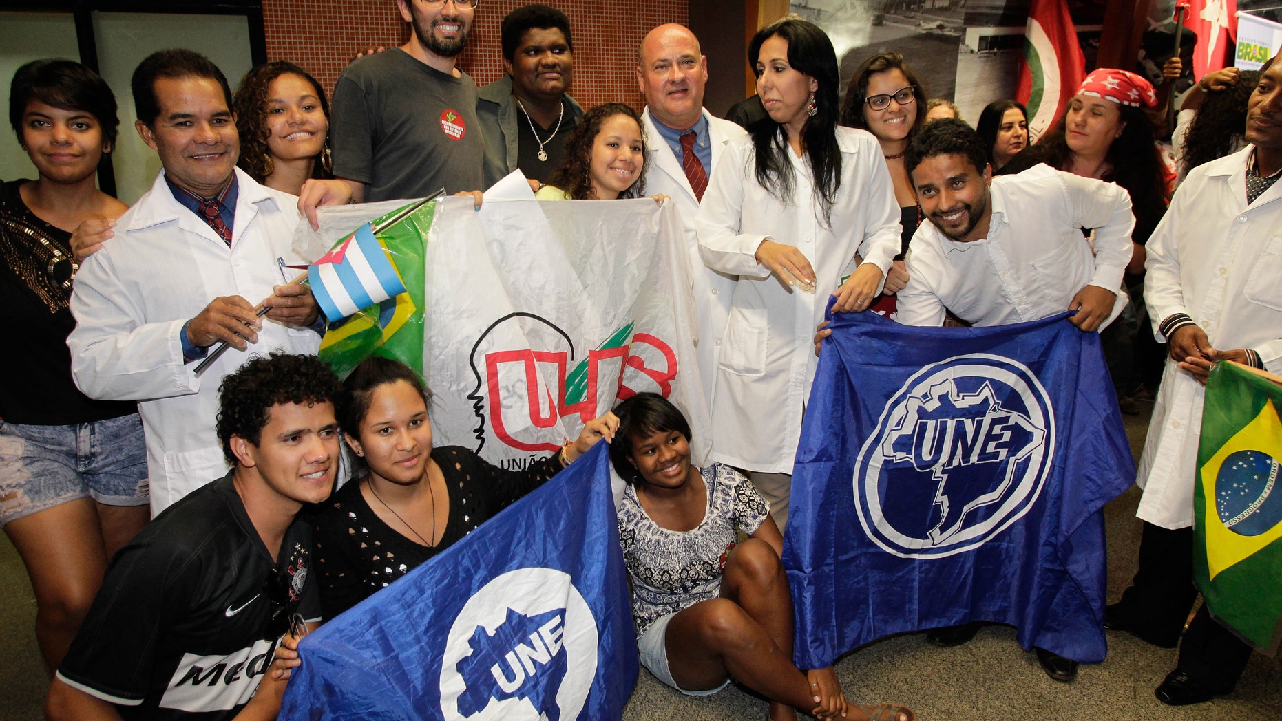Cuban doctors pose for a photo with Brazilian students after their arrival at the International airport, in Brasilia, Brazil, Saturday, Aug. 24, 2013. More than 200 Cuban doctors have arrived in Brazil to work in impoverished areas where physicians and medical services are scarce in Latin America's biggest country, the Health Ministry said Saturday. (AP Photo/Eraldo Peres)