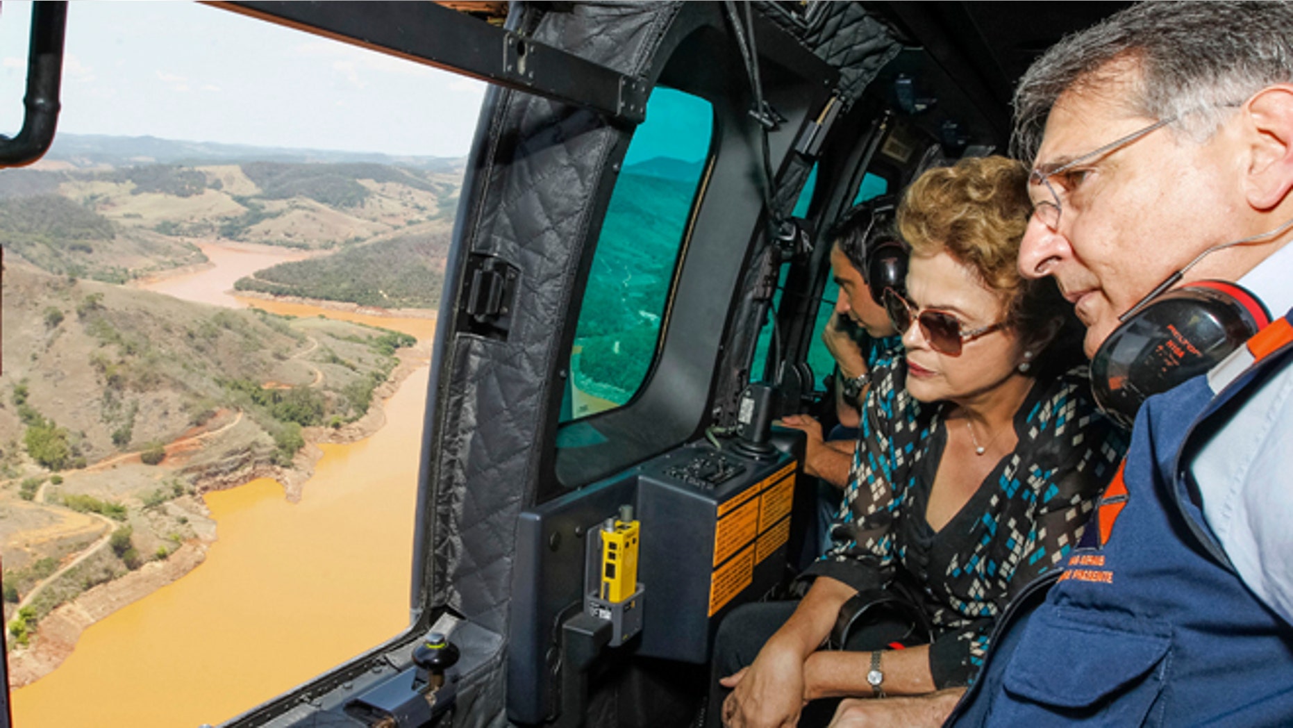 In this photo released by the official web site of the Brazilian Presidency, President Dilma Rousseff accompanied by Minas Gerais state Gov. Fernando Pimentel, looks out over the area of dam bursts at an iron ore mine, in the southeastern Brazilian state of Minas Gerais, Thursday, Nov. 12, 2015. Last week dam failures unleashed a deadly wave of viscous mud that all but erased a hamlet and contaminated a key river. Rousseff says the mining company, Samarco, will be made to pay for the cleanup. (Roberto Stuckert Filho/Brazil Presidential Press Office via AP)