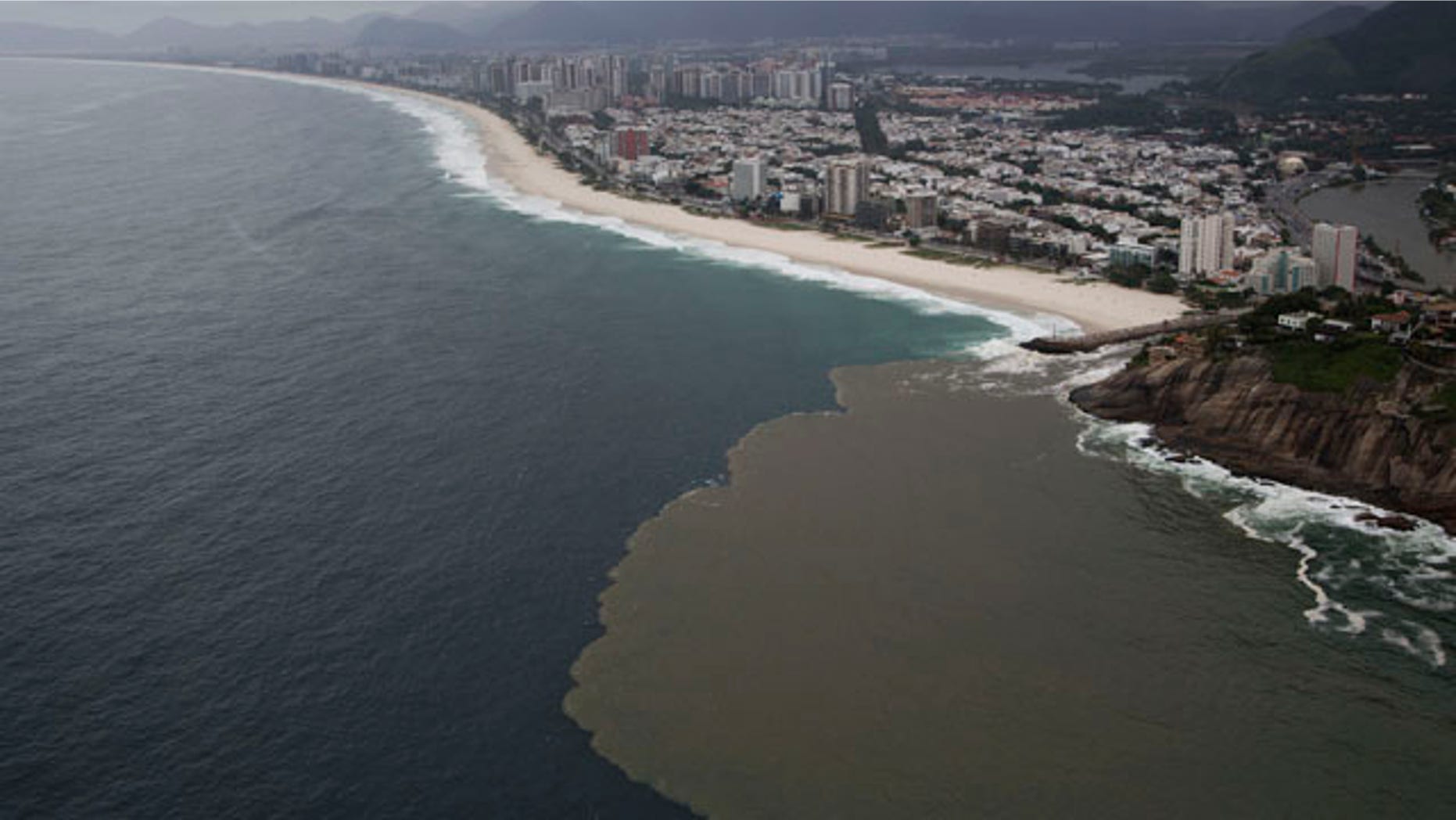 March 23, 2015: This aerial view shows polluted water flowing from the Barra channel to the Barra beach, in Rio de Janeiro, Brazil. (AP Photo/Felipe Dana)