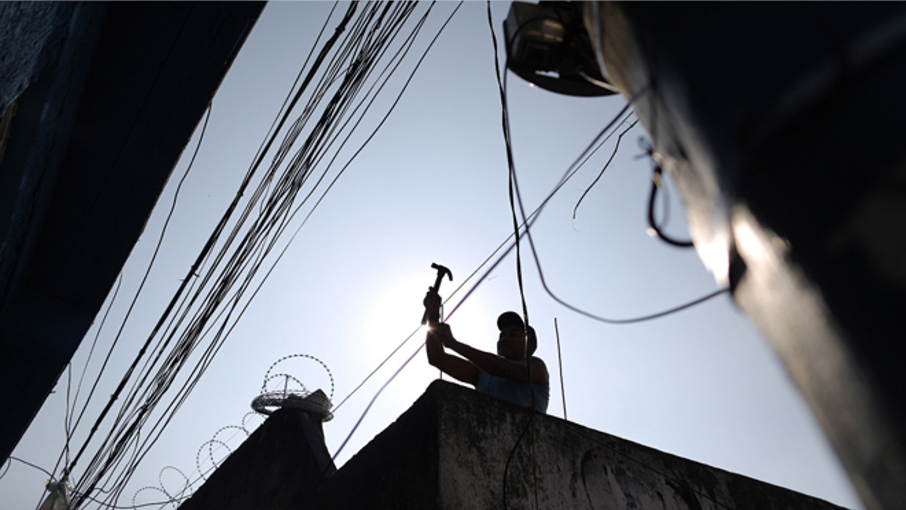 FILE - In this July 2, 2014 file photo, a man works on the rooftop of a home at the Providencia slum of Rio de Janeiro, Brazil. Brazil has slipped into recession, with government figures released Friday, Aug. 29, 2014 showing gross domestic product contracting for a second consecutive quarter. Brazil last experienced a recession between October 2008 and February 2009. (AP Photo/Leo Correa, File)