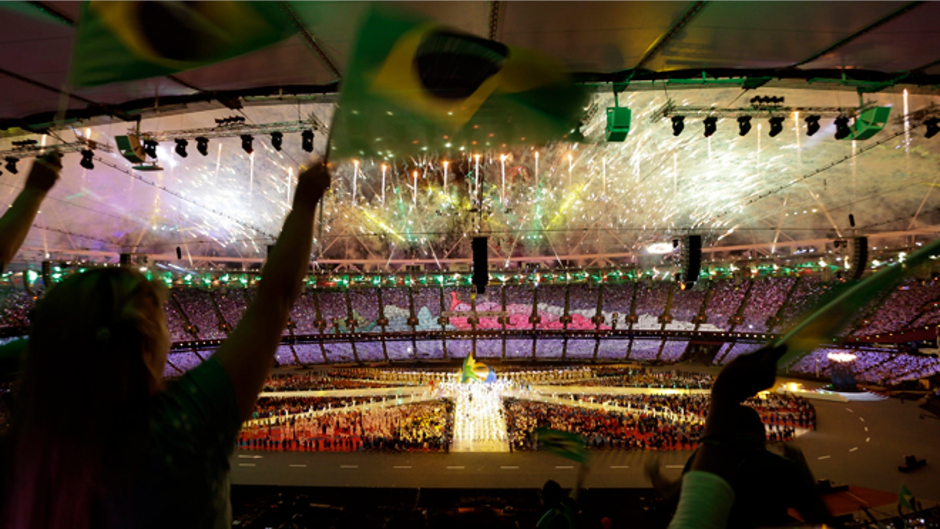 Spectators wave Brazilian flags as fireworks explode over the Olympic stadium during the Closing Ceremony at the 2012 Summer Olympics, Sunday, Aug. 12, 2012, in London. (AP Photo/Hassan Ammar)
