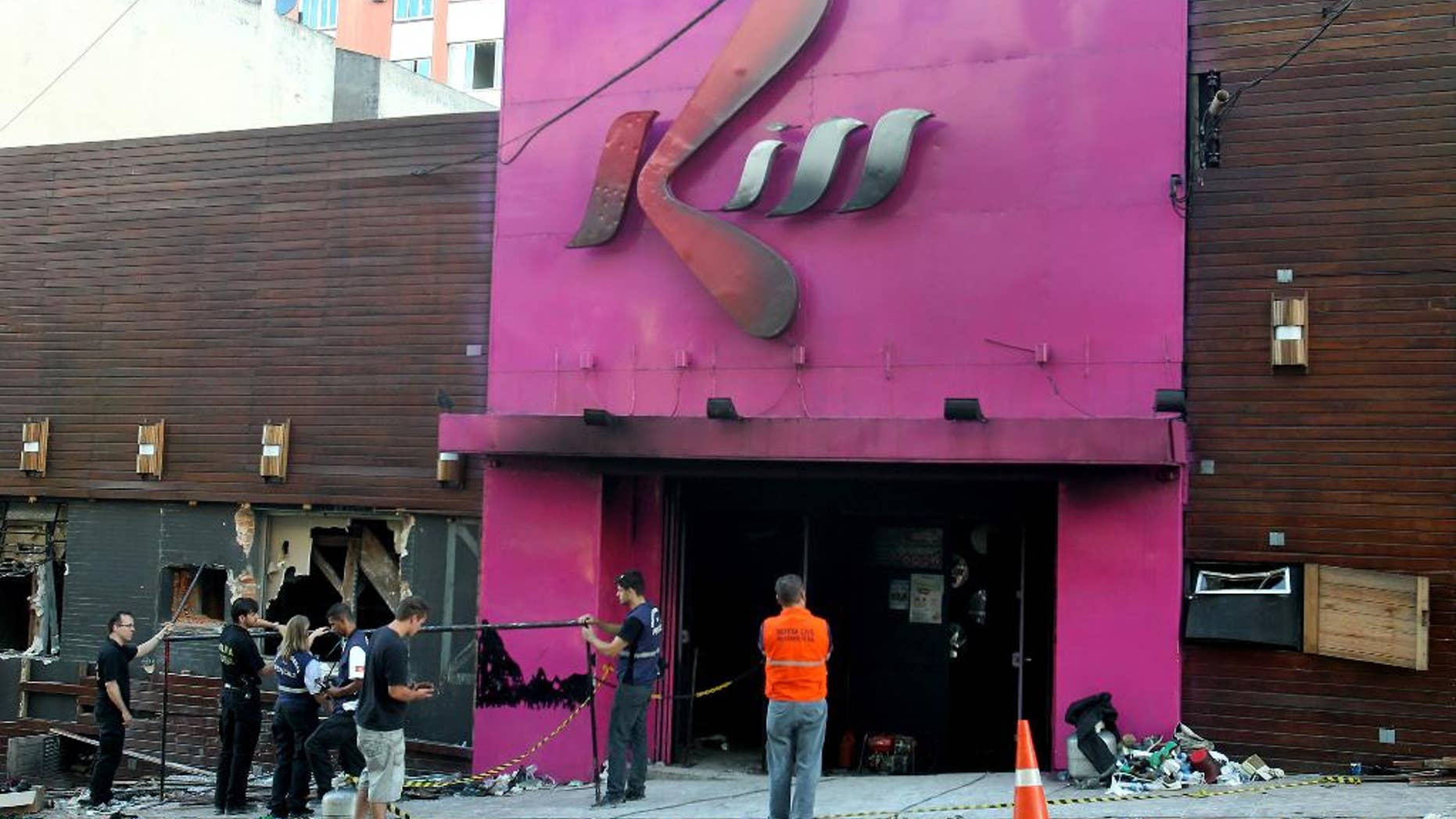 FILE - In this Jan. 27, 2013 file photo, police investigators inspect the entrance of the Kiss nightclub after a fire inside the club in Santa Maria city, Rio Grande do Sul state, Brazil. A court on Wednesday, June 3, 2015 convicted and sentenced to one year in jail two of the eight firefighters on trial for the nightclub fire that killed more than 200 people. The firefighters had been charged with negligence and with falsifying public documents related to the club's fire permit. (AP Photo/Nabor Goulart, File)