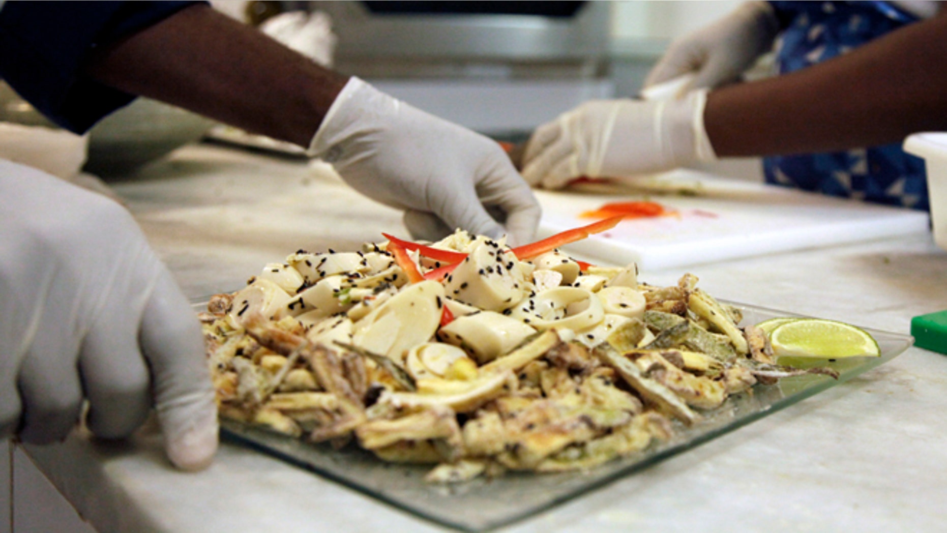 In this May 6, 2016 photo, cooks prepare meals during the food-testing of the Olympic menu in Rio de Janeiro, Brazil. Diners will choose from five different buffets: Brazilian, Asian, International, Pasta and Pizza, Halal and Kosher. (AP Photo/Renato Spyrro)