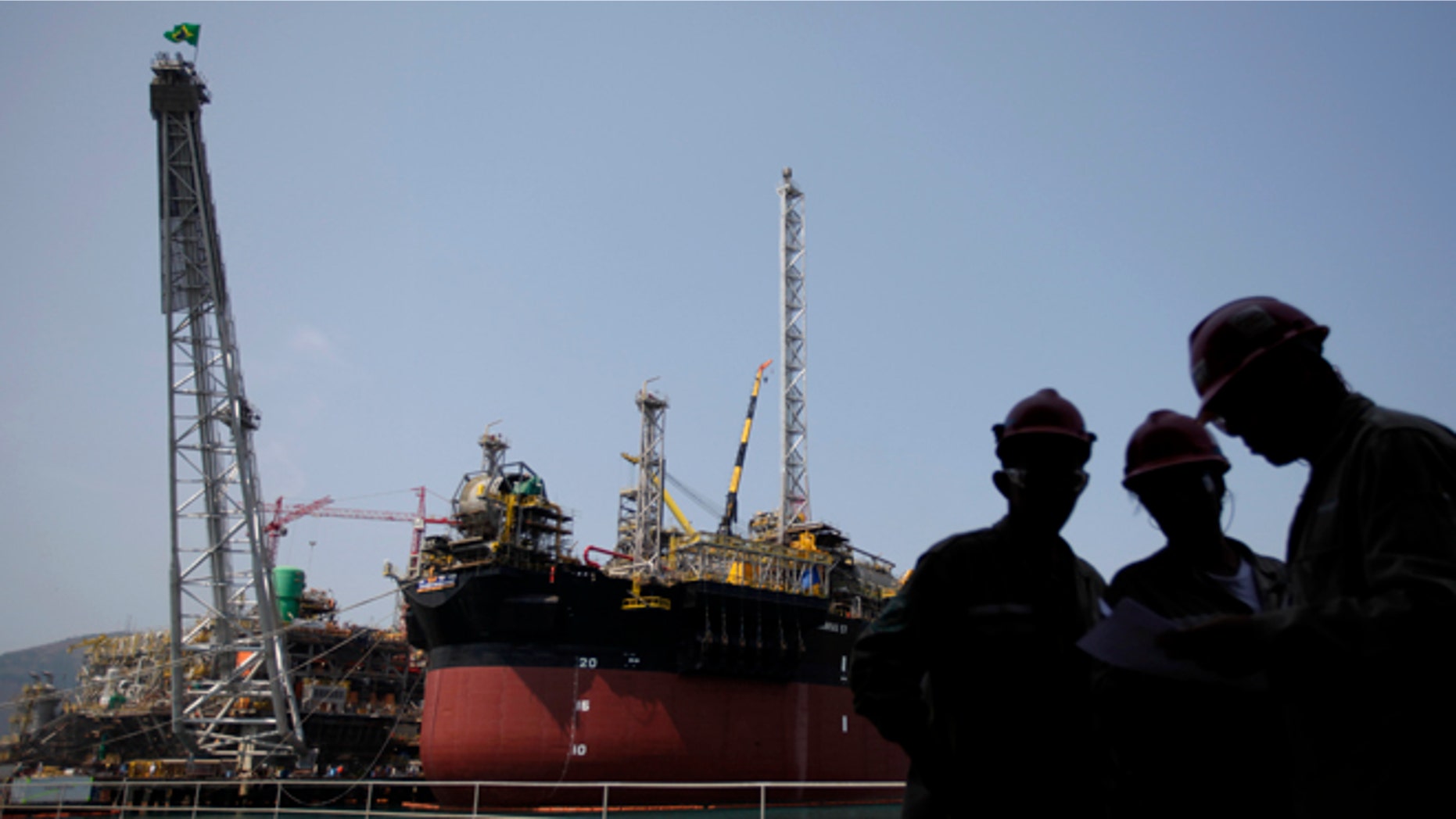 FILE - In this Sept. 22, 2010 file photo, workers stand by the construction of Petrobras oil platforms in the BrasFels shipyard in Angra dos Reis, Brazil. Brazil's state-run oil company reported on Monday, March 21, 2016 a record quarterly loss due to a large reduction in some of its assets amid lower oil prices. (AP Photo/Felipe Dana, File)