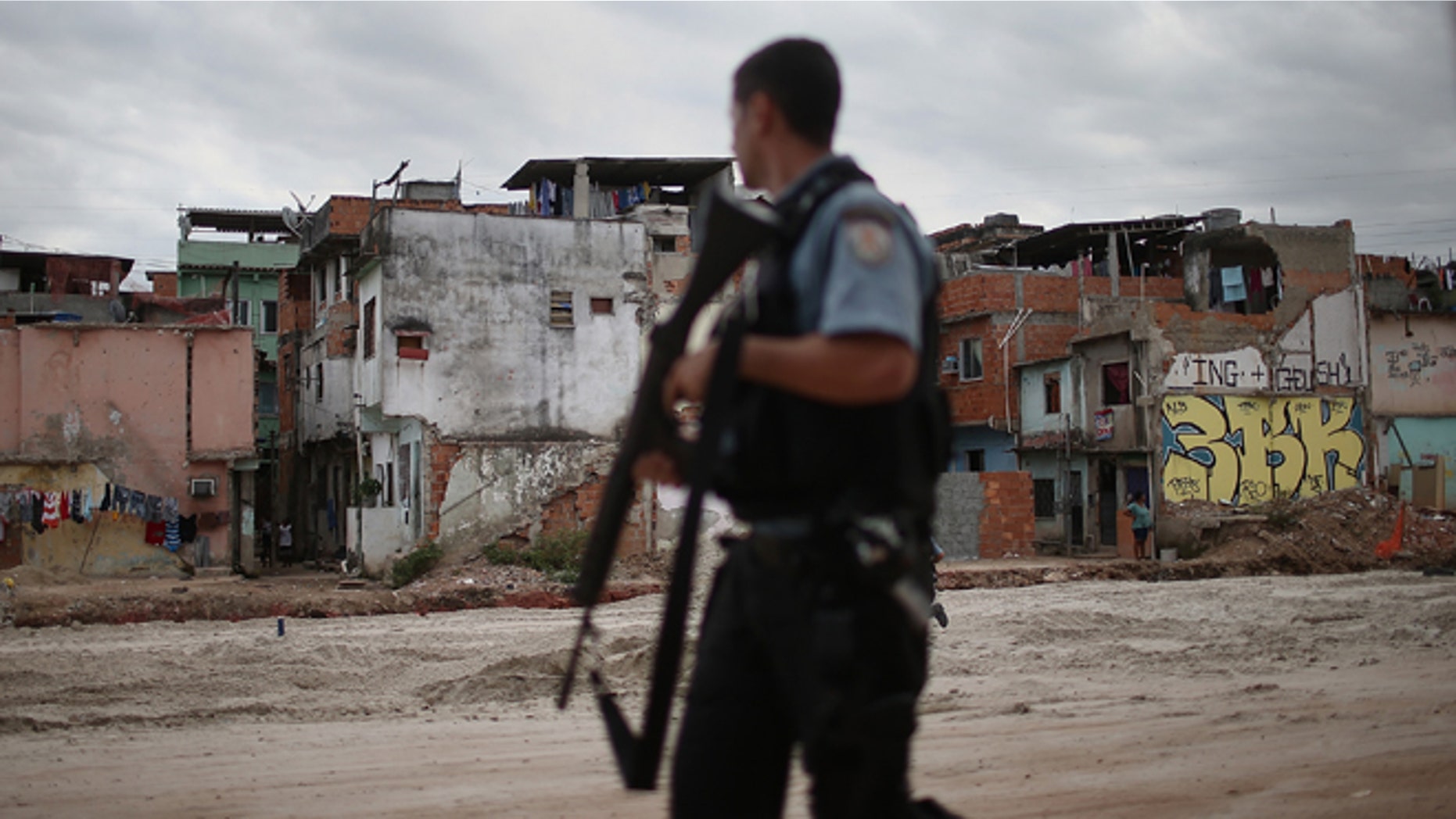 RIO DE JANEIRO, BRAZIL - MAY 27: A police officer patrols past an area where homes were torn down in the Manguinhos community on May 27, 2014 in Rio de Janiero, Brazil. Residents from one section of the 'favela', visited by Pope Francis in July 2013, have been affected by construction from the improvement works project begun in 2008. A full sanitation system has yet to be built. Evictions and demolitions have been occurring in Rio favelas ahead of the 2014 FIFA World Cup and Rio 2016 Olympic Games in spite of a housing shortage in the city. Rio's housing and urban planning goals include a planned five percent reduction of areas occupied by favelas by 2016. Alternative affordable housing, generally on the peripheries of the city, is unable to meet demand and some residents complain they have not received adequate compensation for demolished homes. (Photo by Mario Tama/Getty Images)
