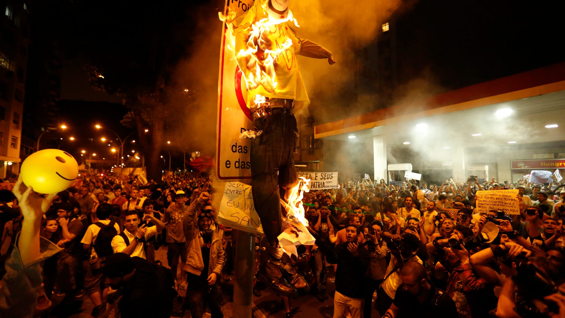 Protesters burn a puppet that symbolizes Rio de Janeiro State Governor Sergio Cabral during a demonstration near Guanabara Palace in Rio de Janeiro, Brazil, Monday, July 22, 2013.