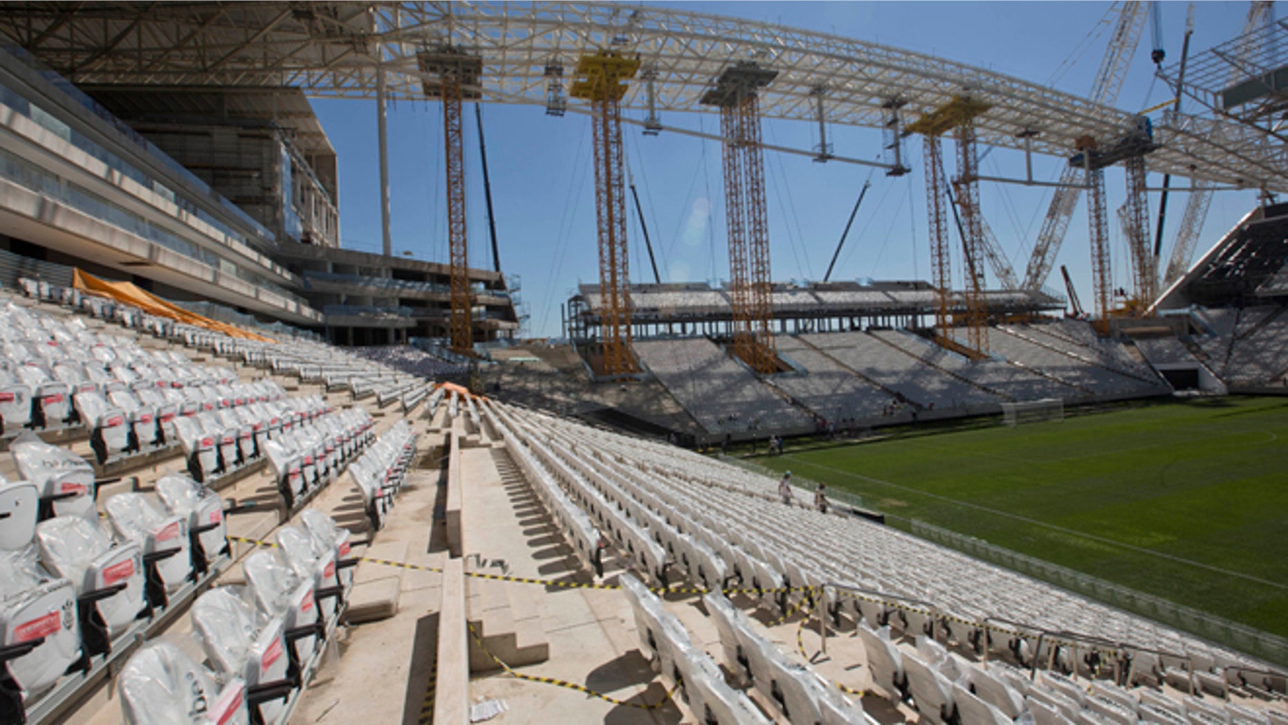 Men work at the Itaquerao, the stadium that will host the World Cup opener in less than three months in Sao Paulo, Brazil, Saturday, March 15, 2014. The Itaquerao was one of the six stadiums that were supposed to be finished by the end of 2013, but a crane collapse that killed two workers in November caused significant delays to the venue where Brazil will play Croatia on June 12. The stadium is not expected to be ready before mid-April. (AP Photo/Andre Penner)