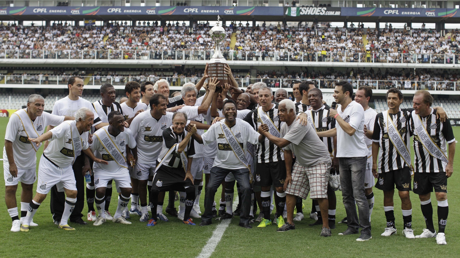 Pelé, center, with other former Santos soccer players hold up the Libertadores championship trophy during during the centennial anniversary celebration of the team in Santos, Brazil, Saturday, April 14, 2012. Santos, the Brazilian club which ruled football with "The King" Pele in the 1960's, turns 100 with a rich history to show, including many major titles and remarkable victories that make the club one of the most successful in football. (AP Photo/Nelson Antoine)