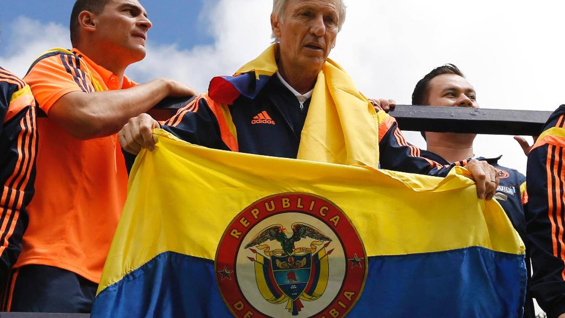 FILE - In this July 6, 2014 file photo, Colombia's coach Jose Pekerman, from Argentina, holds a Colombian flag as the team parades before supporters as they are welcomed home from the World Cup, in Bogota, Colombia, following their loss to Brazil in the quarterfinals. Colombia's Football Federation announced on Tuesday, Aug. 19, 2014 that Pekerman will stay on as coach for the national selection. (AP Photo/Fernando Vergara, File)