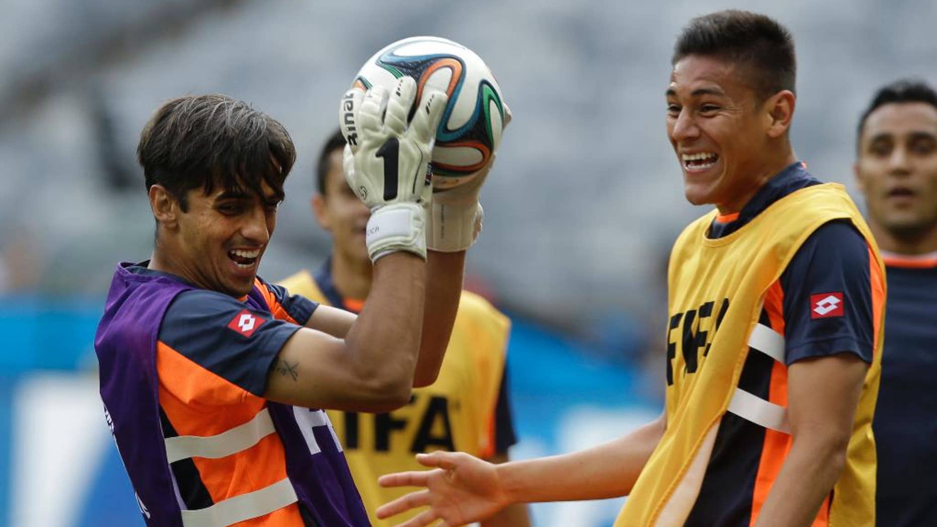 Costa Rica's captain and attacking player Bryan Ruiz, left, catches the ball whilst playing as a goalkeeper during an official training session the day before the group D World Cup soccer match between Costa Rica and England at the Mineirao Stadium in Belo Horizonte, Brazil, Monday, June 23, 2014. (AP Photo/Matt Dunham)