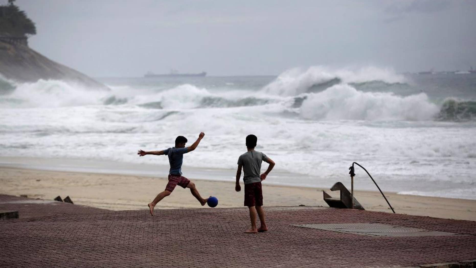 FILE - In this June 20, 2014 file photo, boys play football as waves break on Sao Conrado beach in Rio de Janeiro, Brazil. World Surf League spokesman Dave Prodan said in an emailed statement Wednesday, April 29, 2015, that Sao Conrado beach had to be removed from its venue list “due to pollution issues.” The beach had been a backup for the May 11-22 Rio Pro event, to be used in case of sub-par waves or other issues at the primary venue, nearby Barra da Tijuca beach. (AP Photo/Matt Dunham, File)