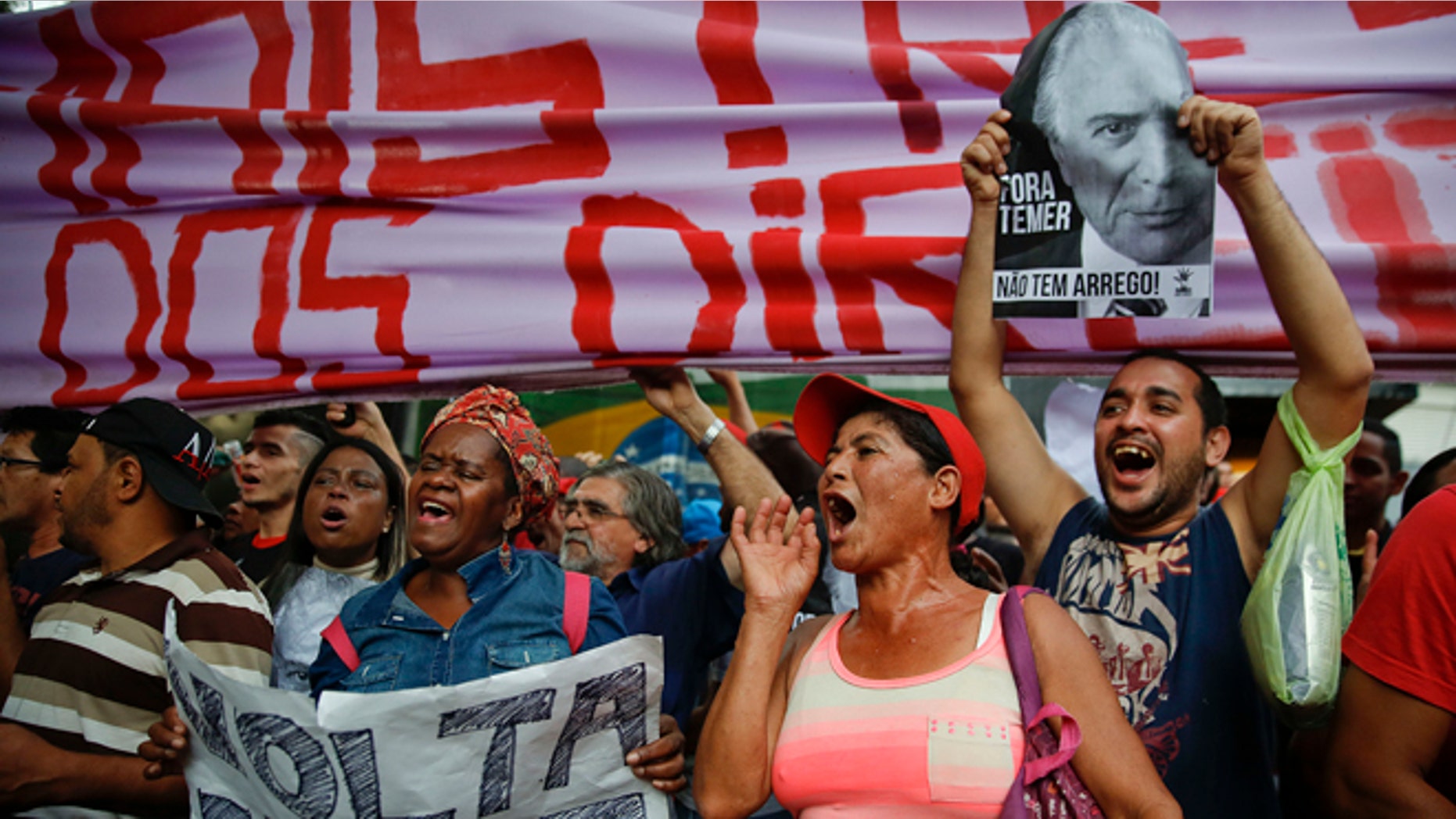 With signs that read in Portuguese "Dilma come back" and "Temer Out," demonstrators shout slogans during a protest against Brazil's acting President Michel Temer and in support of Brazil's suspended President Dilma Rousseff, close to Temer's residence in São Paulo, Brazil, Sunday, May 22, 2016. Temer took office after Rousseff was suspended for up to 180 days while the Senate holds an impeachment trial. (AP Photo/Andre Penner)