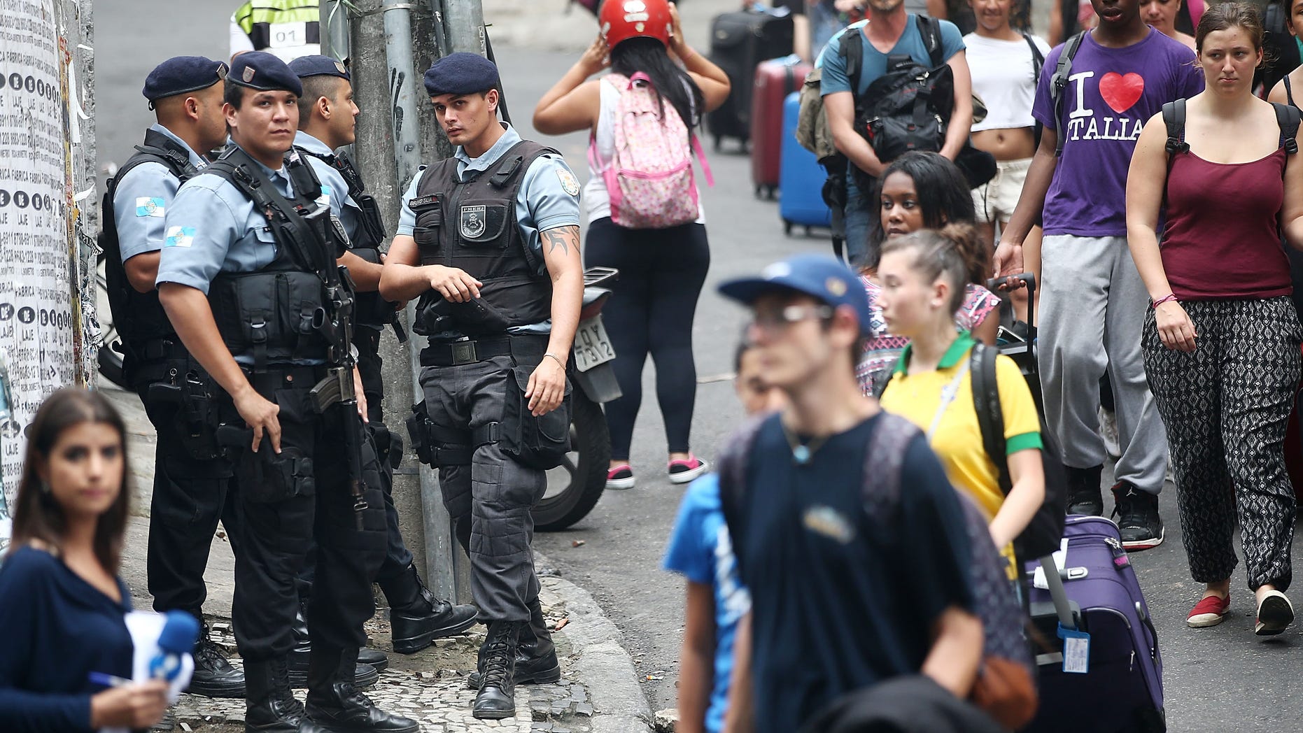 RIO DE JANEIRO, BRAZIL - APRIL 23: Police keep watch as tourists carry their luggage to a tour bus near the pacified Pavao-Pavaozinho community, just blocks from Copacabana Beach, on April 23, 2014 in Rio de Janeiro, Brazil. Protests and shootings broke out yesterday, resulting in the shooting death of a man, following the discovery of dancer Douglas Rafael da Silva's body, who protesters allege was beaten by police, in the pacified 'favela'. (Photo by Mario Tama/Getty Images)