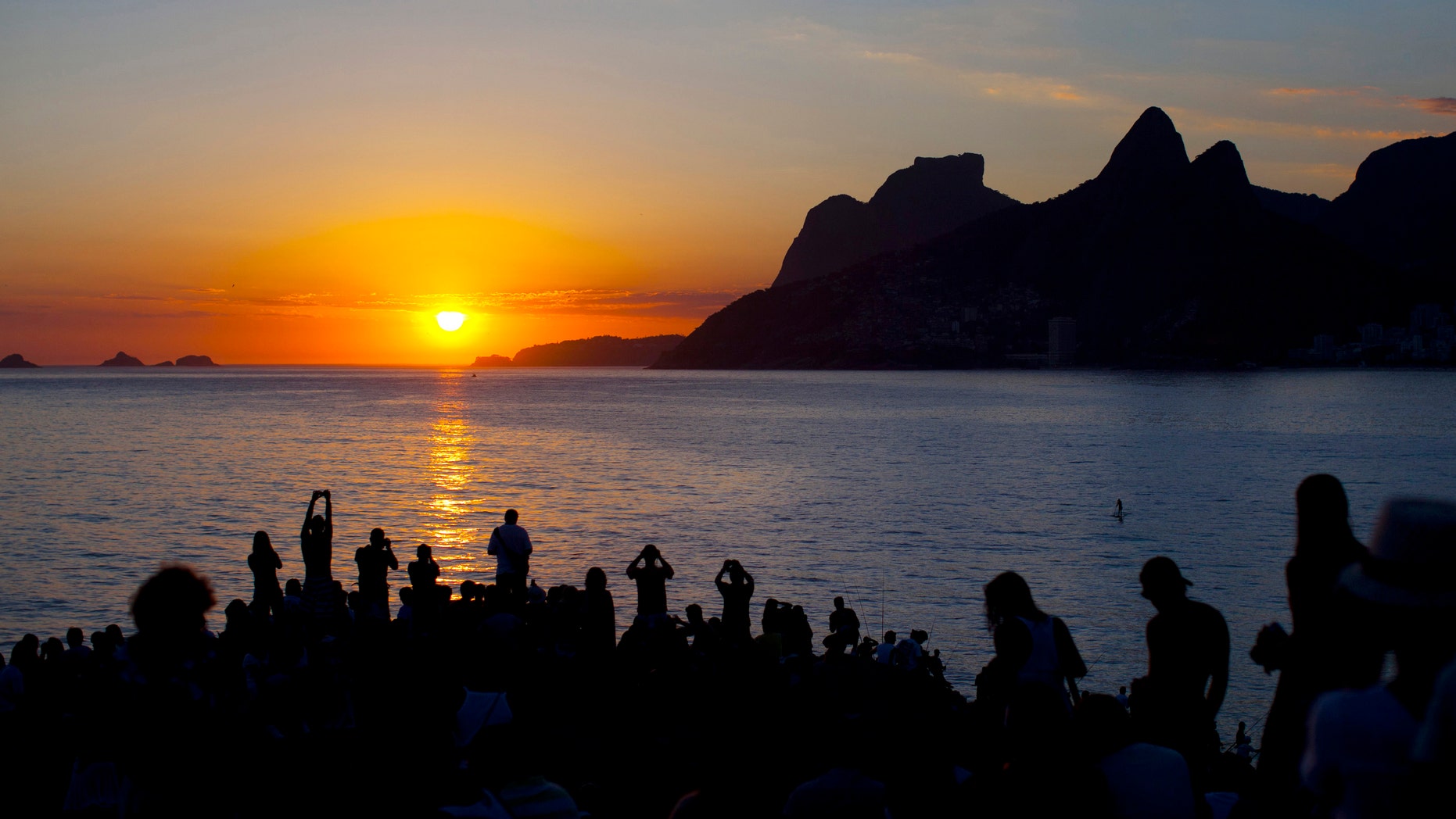 In this photo taken on Feb. 6, 2012, people watch the sun set and take pictures from Arpoador beach in Rio de Janeiro, Brazil. Rio is a city of contrasts, where vastly different worlds rub shoulders, and the unexpected lies lurking around every corner. (AP Photo/Felipe Dana)