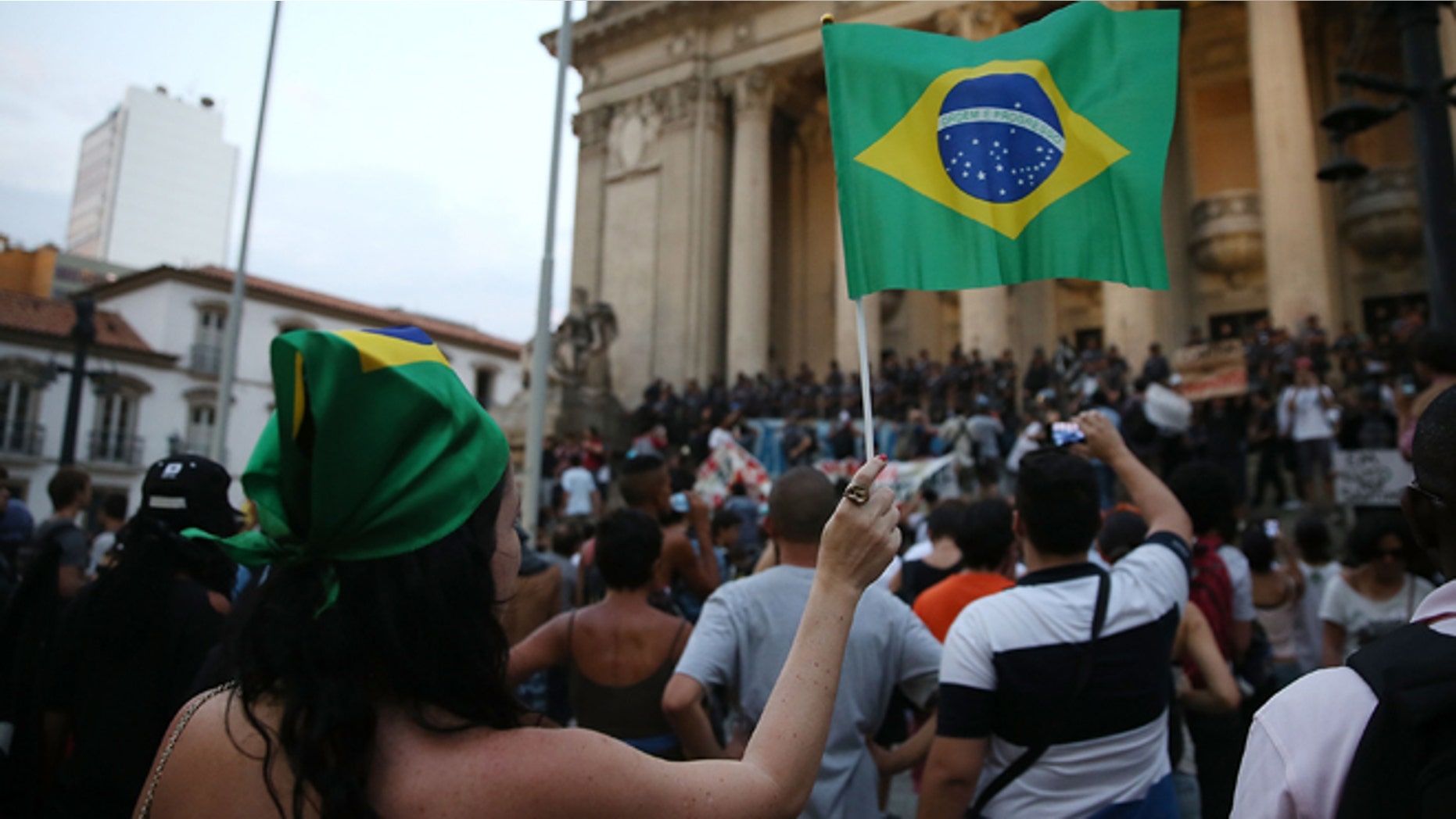 RIO DE JANEIRO, BRAZIL - FEBRUARY 10: Protesters demonstrate against the new increase in public bus fares as police keep watch on February 10, 2014 in Rio de Janeiro, Brazil. Widespread protests began in the country last June following a different bus fare increase in Sao Paulo. A similar bus fare protest was held last week in Rio, resulting in violence, but this protest was largely peaceful. Civil unrest continues in the country as it prepares to host the 2014 World Cup. (Photo by Mario Tama/Getty Images)