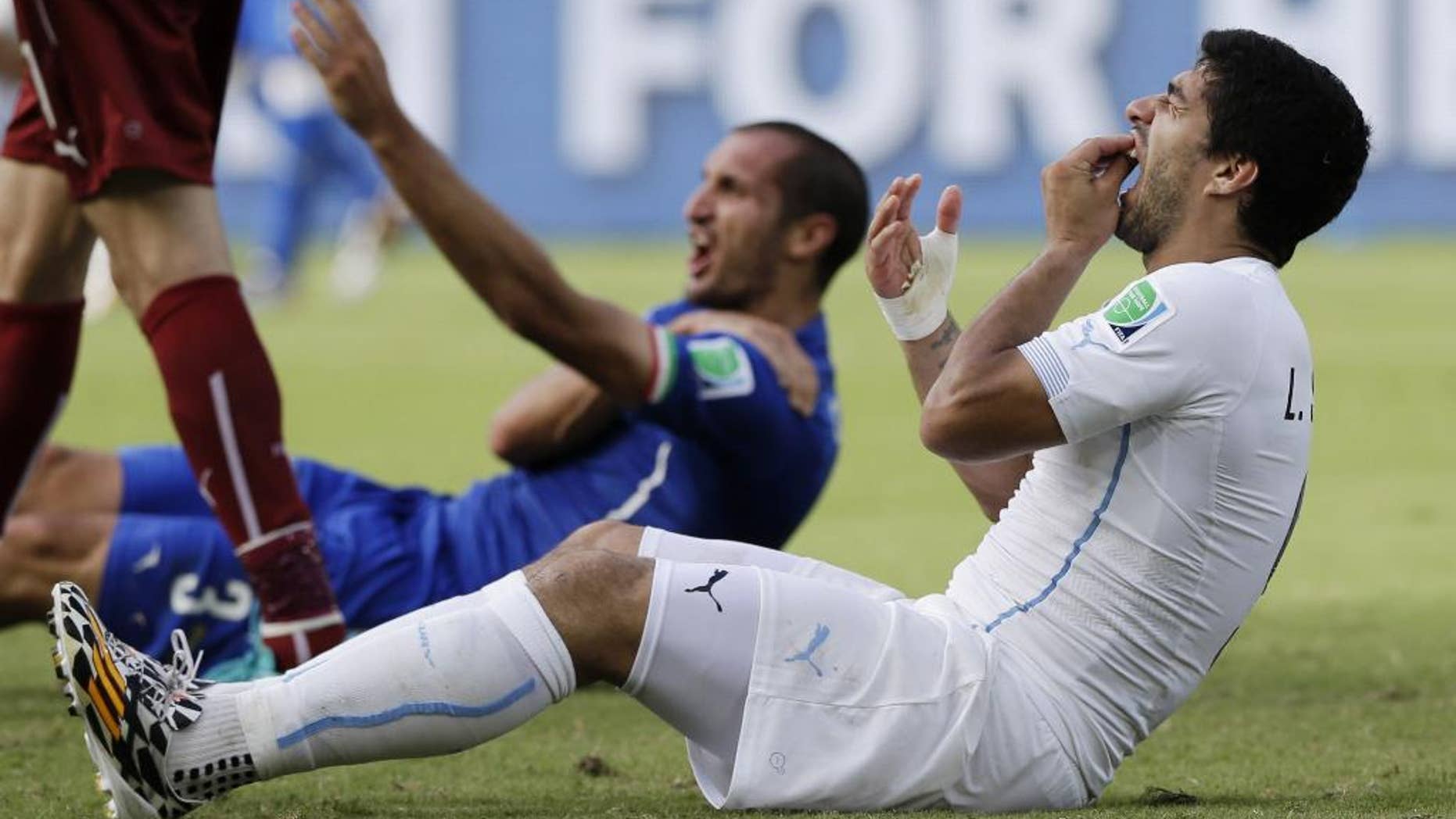 FILE - In this June 24, 2014 file photo, Uruguay's Luis Suarez holds his teeth after biting Italy's Giorgio Chiellini's shoulder during the group D World Cup soccer match between Italy and Uruguay at the Arena das Dunas in Natal, Brazil. On Thursday, June 26, 2014, FIFA banned Suarez for 9 games and 4 months for biting his opponent at the World Cup. (AP Photo/Ricardo Mazalan, File)
