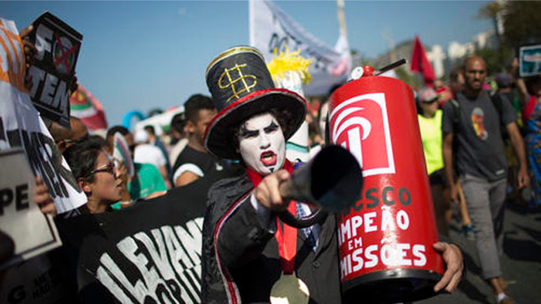 A demonstrator in a costume depicting a banker and holding a replica of a fire extinguisher for putting out the "flame" of an imitation Olympic torch, takes part in a protest against the interim Brazilian president Michel Temer, and the Rio's 2016 Summer Olympics, on the route of the Olympic torch, at the Copacabana beach, in Rio de Janeiro, Brazil, Friday, Aug. 5, 2016. (AP Photo/Leo Correa)