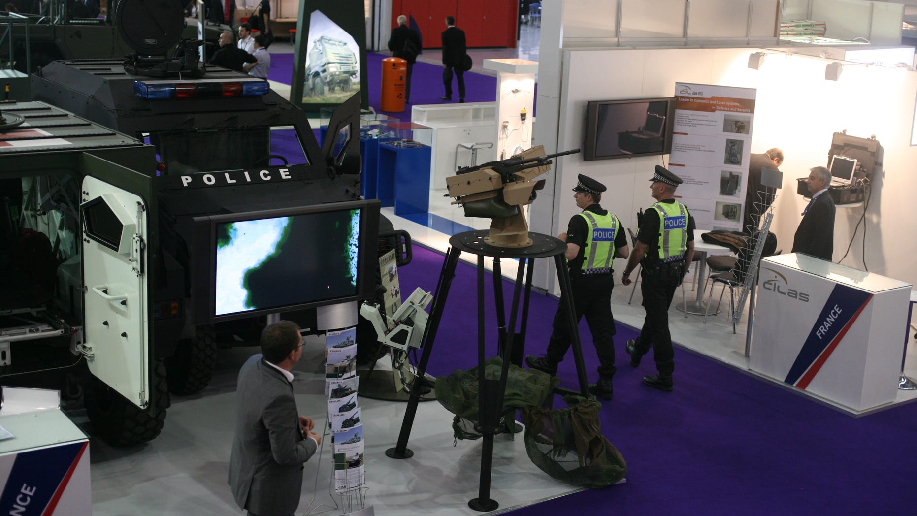 Police walk past a French Panhard armored personnel vehicle, with police markings to underscore its use beyond traditional battle fields as the Defence & Security Equipment International show gets underway in London, Tuesday Sept. 13, 2011.
