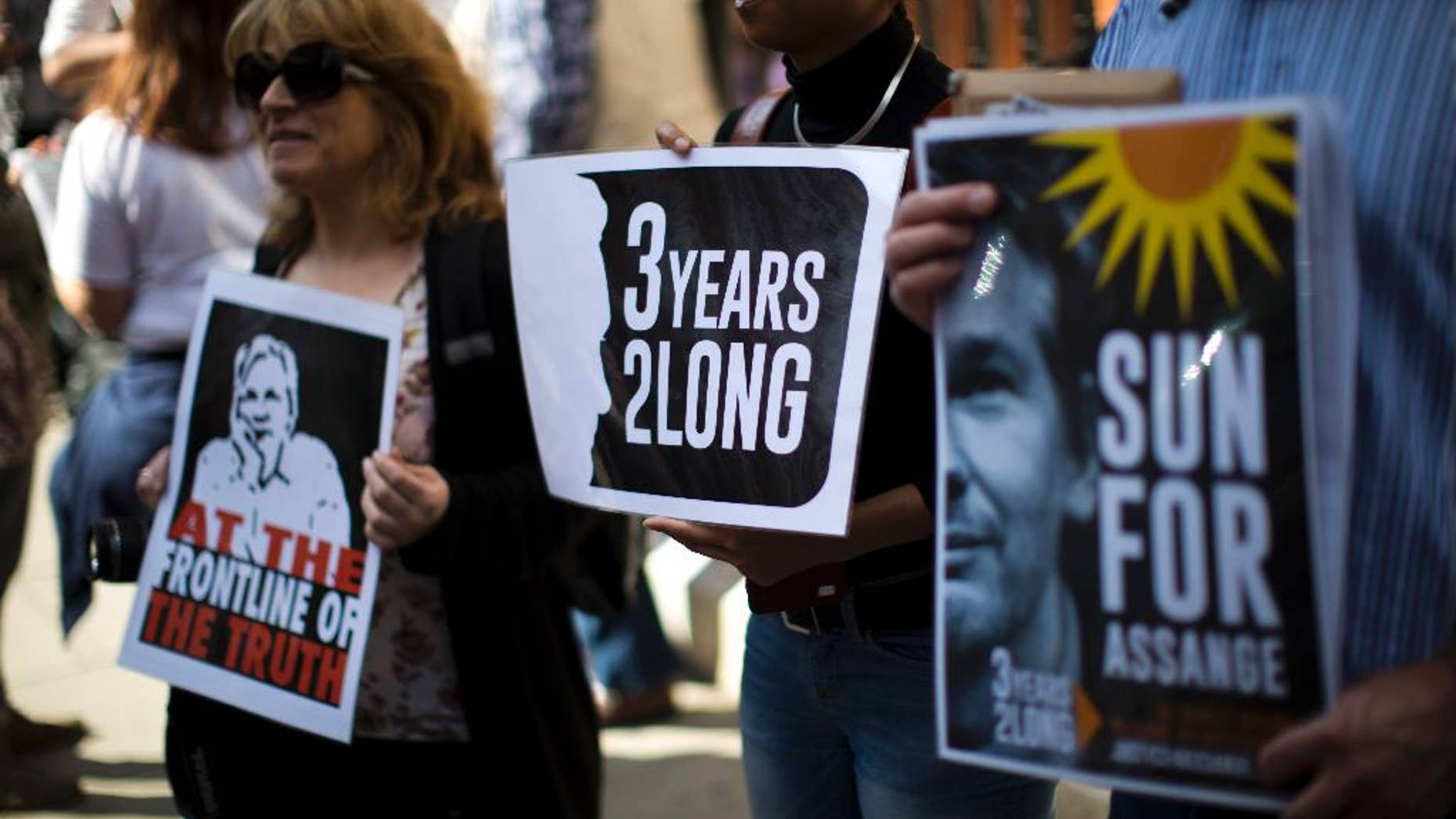 Supporters of WikiLeaks founder Julian Assange hold placards during a vigil across the street from the Ecuador embassy in London, Friday, June 19, 2015. Julian Assange is marking the third anniversary of his stay inside Ecuador's London embassy. The WikiLeaks founder entered the building on June 19, 2012, to avoid extradition to Sweden for questioning about alleged sexual assaults. British police stand outside, ready to arrest him if he leaves. (AP Photo/Matt Dunham)
