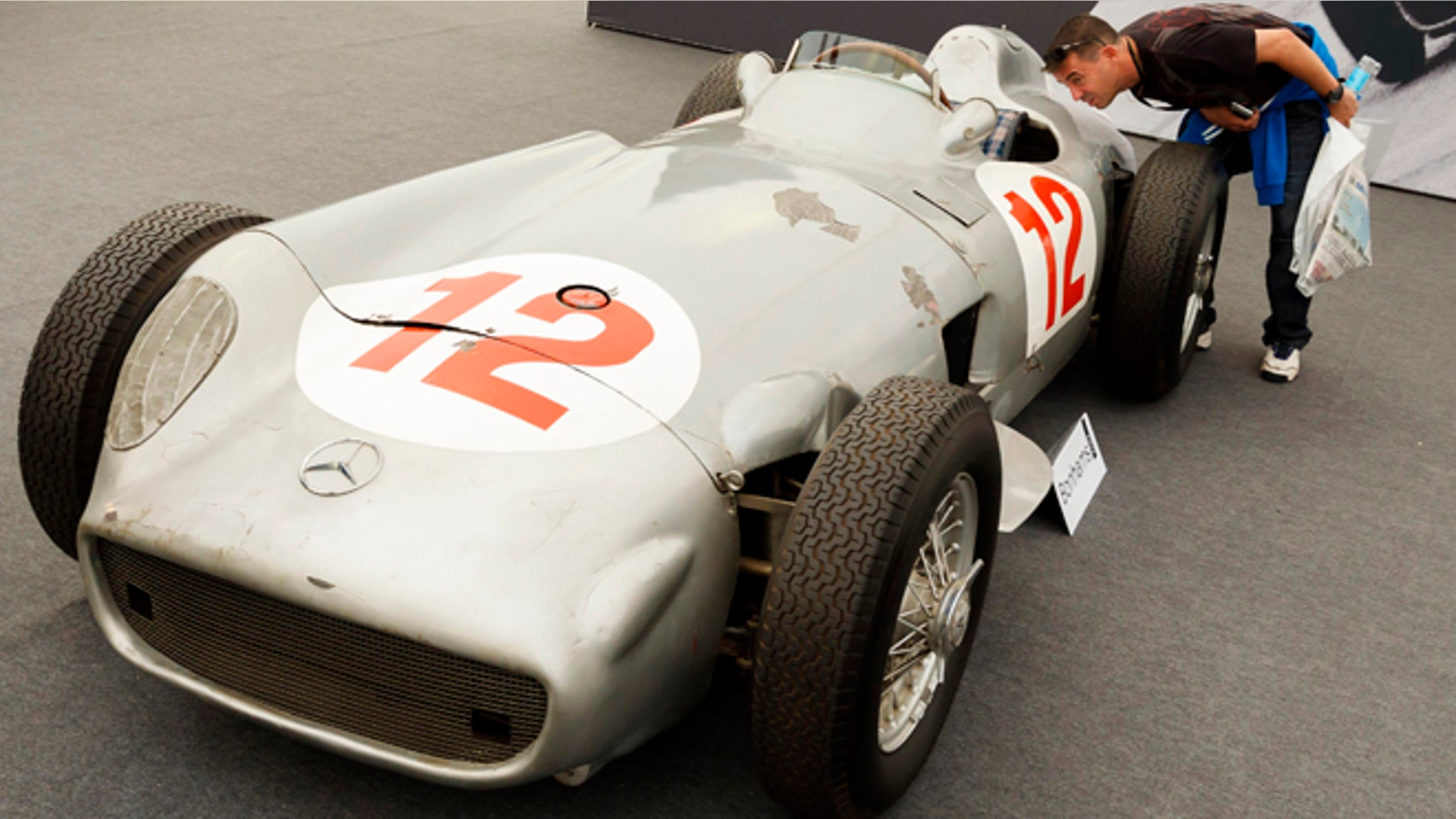 In this photo taken Thursday, July 11, 2013, a man looks inside a 1954 Mercedes-Benz W196 single-seater race car once driven by Formula One legend Juan Manuel Fangio as it is displayed by an auction house at the Festival of Speed in Goodwood, near Chichester, England. Fangio, who drove the car to victories in the 1954 German and Swiss Grand Prix race, sold for 19.6 million pounds ($29.6 million) at auction on Friday. (AP Photo/PA, Chris Ison) UNITED KINGDOM OUT, NO SALES, NO ARCHIVE