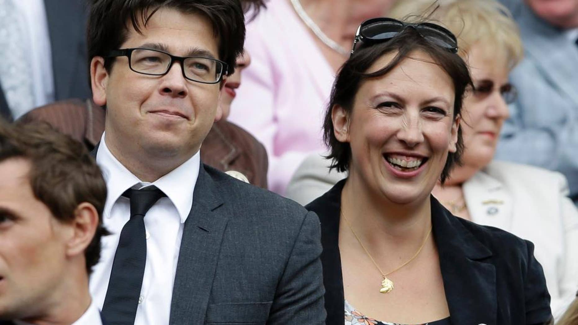 FILE - This is a Saturday, July 7, 2012 file photo of British comedian Michael McIntyre, left, and comedian Miranda Hart, as they watch Serena Williams of the United States face Agnieszka Radwanska of Poland in the women's final match at the All England Lawn Tennis Championships at Wimbledon, England. An image of the top of Micheal McIntyre's head has Britons debating the decline of privacy in an age of surveillance. On Wednesday July 15, 2015 the National Police Air Service, which operates camera-equipped helicopters, tweeted an image of a man with a mop of dark hair, asking if people could recognize "a certain energetic funny man." (AP Photo/Kirsty Wigglesworth, File)