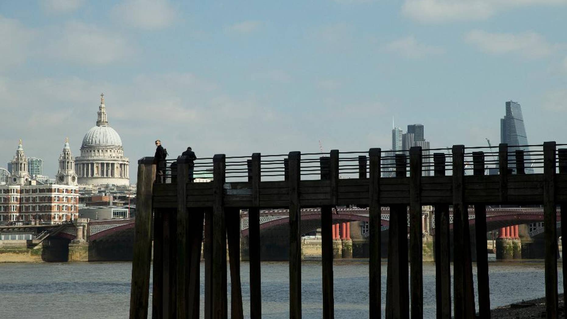Tourists take photos of the River Thames, with St Paul's Cathedral, left, at low tide on the south bank in London, Monday, March 23, 2015. (AP Photo/Alastair Grant)