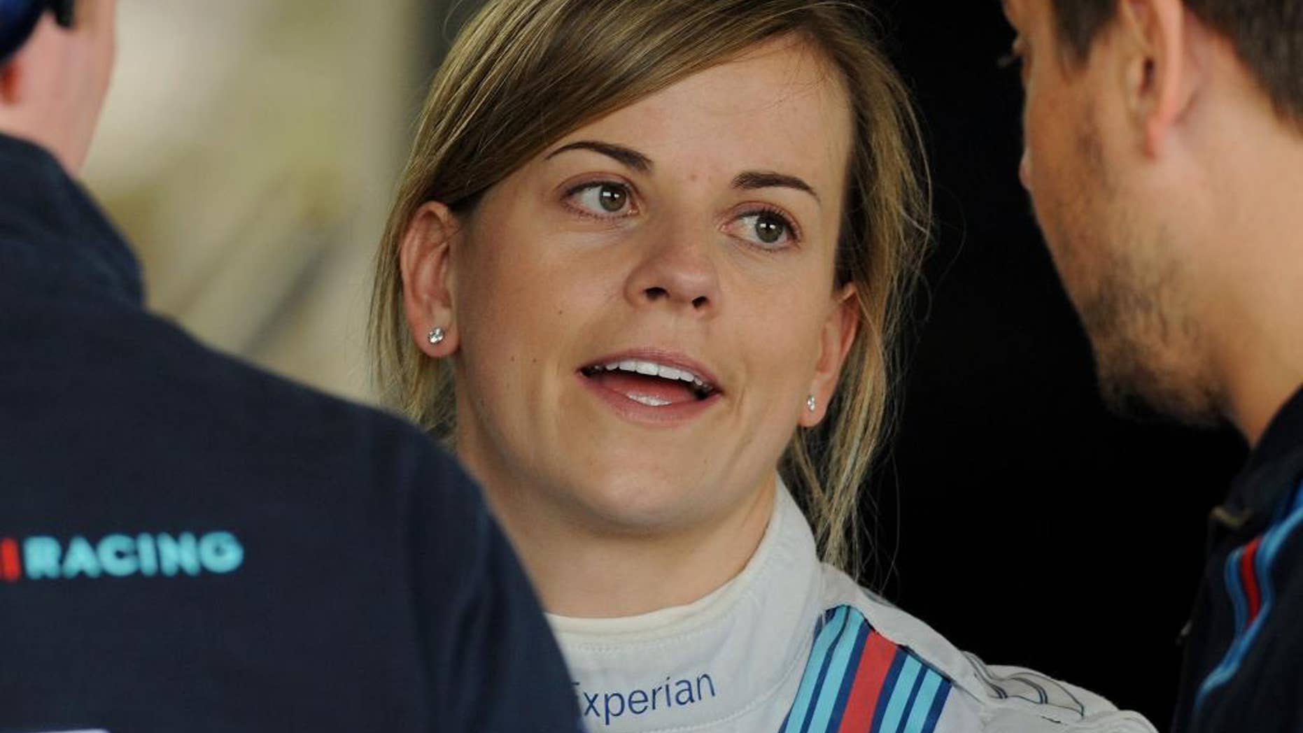 FILE - In this Friday, July 4, 2014 file photo, Scottish Suzie Wolff of Williams, the first woman to take part in a Formula 1 race weekend in 22 years, talks to mechanics in the garage before the first practice session at the British Grand Prix at Silverstone, England. Wolff has been promoted to official test driver for Williams for the 2015 Formula One season, increasing her chances of becoming the first female racer on the grid since 1976, it was announced on Friday, Nov. 28, 2014. (AP Photo/Rui Vieira, File)