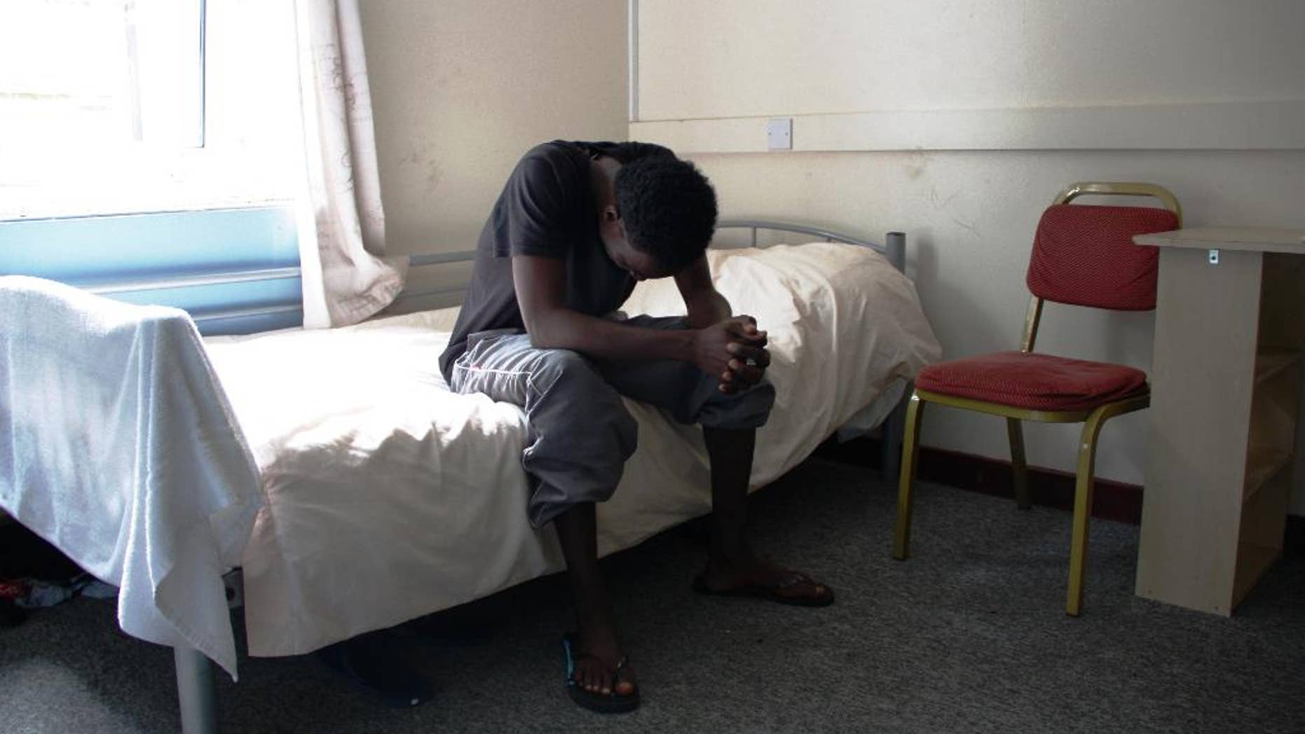 In this photo provided by Kent County Council, a young male refugee sits on a bed at reception centre in the county of Kent in southeast England in early September 2015. The Afghan, Eritrean and Sudanese refugee boys at the centre will be moved again and this time it’s a happy occasion: After months of hardship traversing continents, the teenage refugees are finally on the way to English homes where they can settle down for a long dreamed-of life in Europe. (Kent County Council via AP)