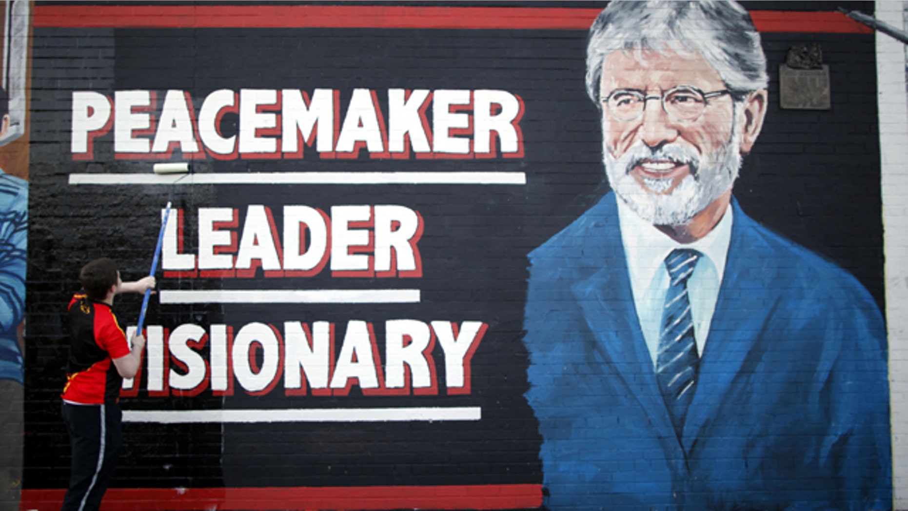 May 2, 2014: A man adds the finishing touch to a newly painted mural of Sinn Fein leader Gerry Adams on the Falls Road, West Belfast, Northern Ireland. (AP Photo/Peter Morrison)