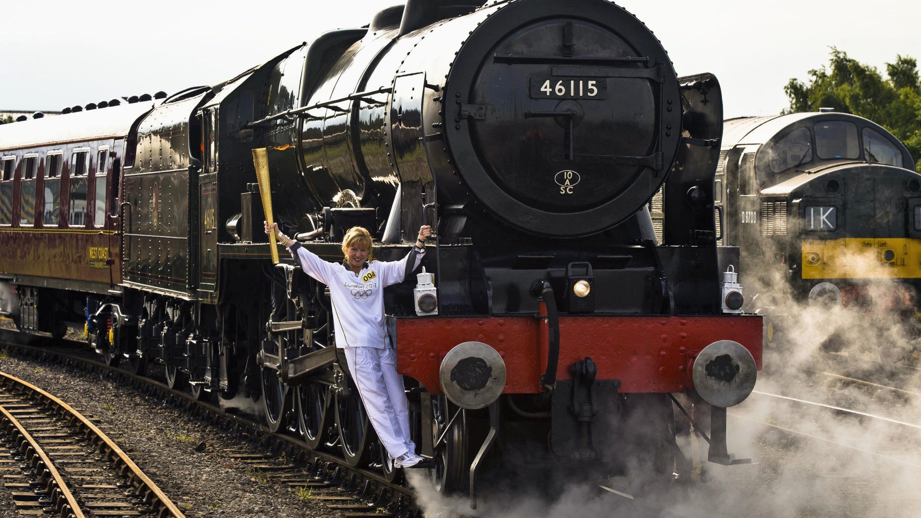 June 20, 2012: Josephine Loughran carrying the Olympic Flame on the Scots Guardsman steam locomotive as they make the journey from York to Thirsk in England on day 33 of the torch relay (AP Photo/Ben Birchall, LOCOG, HO)