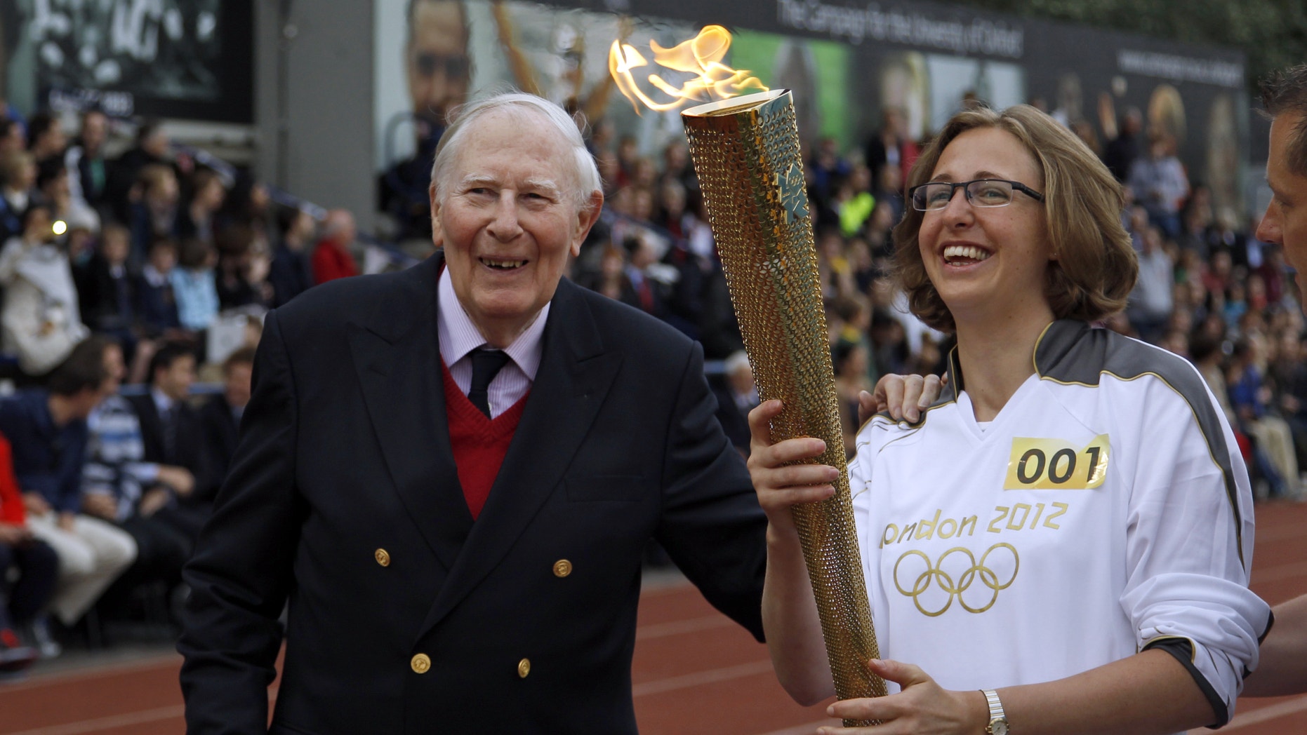 July 10, 2012: The Olympic Flame is passed between Sir Roger Bannister and Oxford doctoral student Nicola Byrom on the running track at Iffley Road Stadium in Oxford, England.